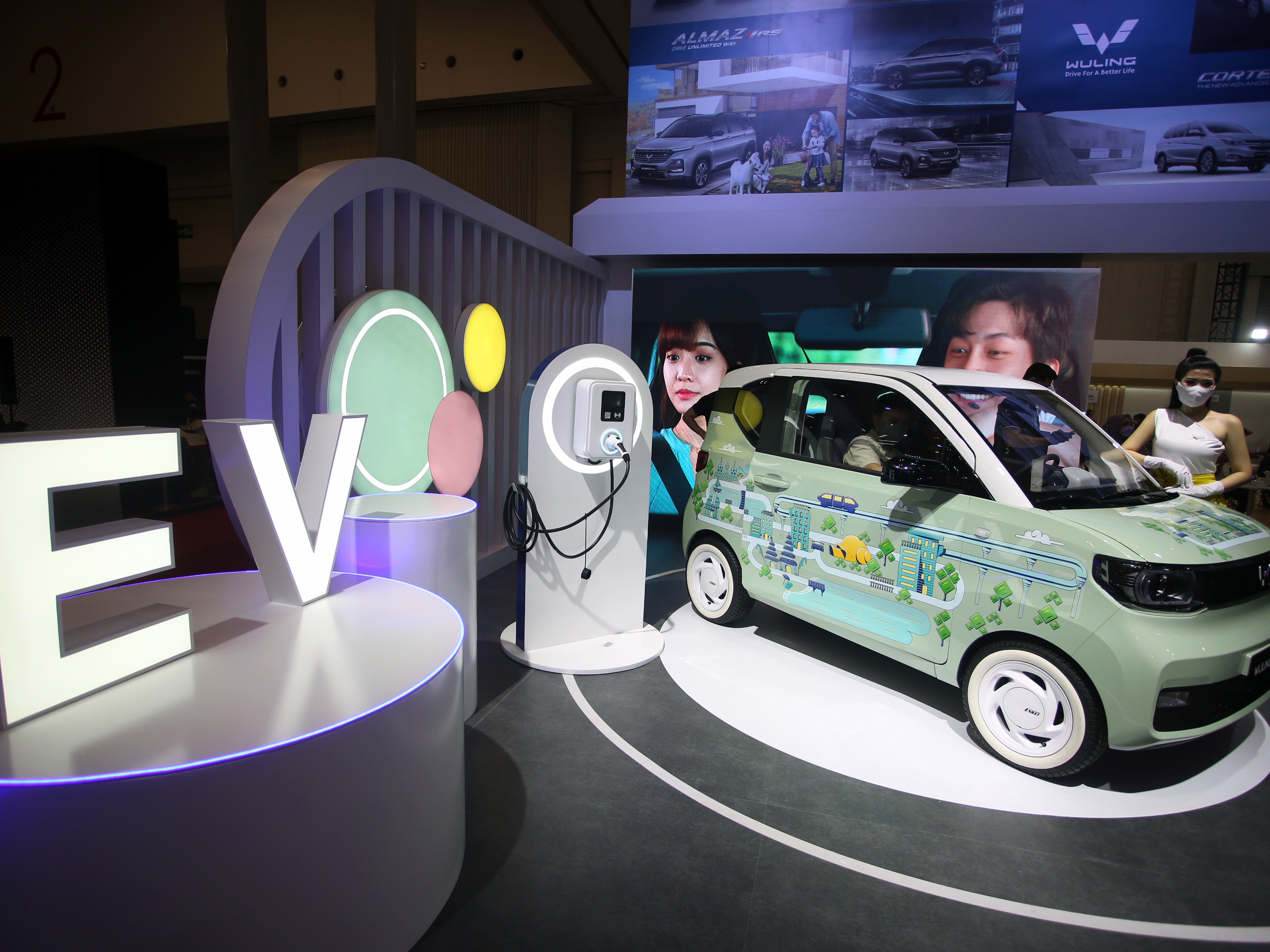 Model berfoto di samping mobil listrik Wuling GSEV yang dipamerkan pada ajang pameran Gaikindo Indonesia International Auto Show 2021.