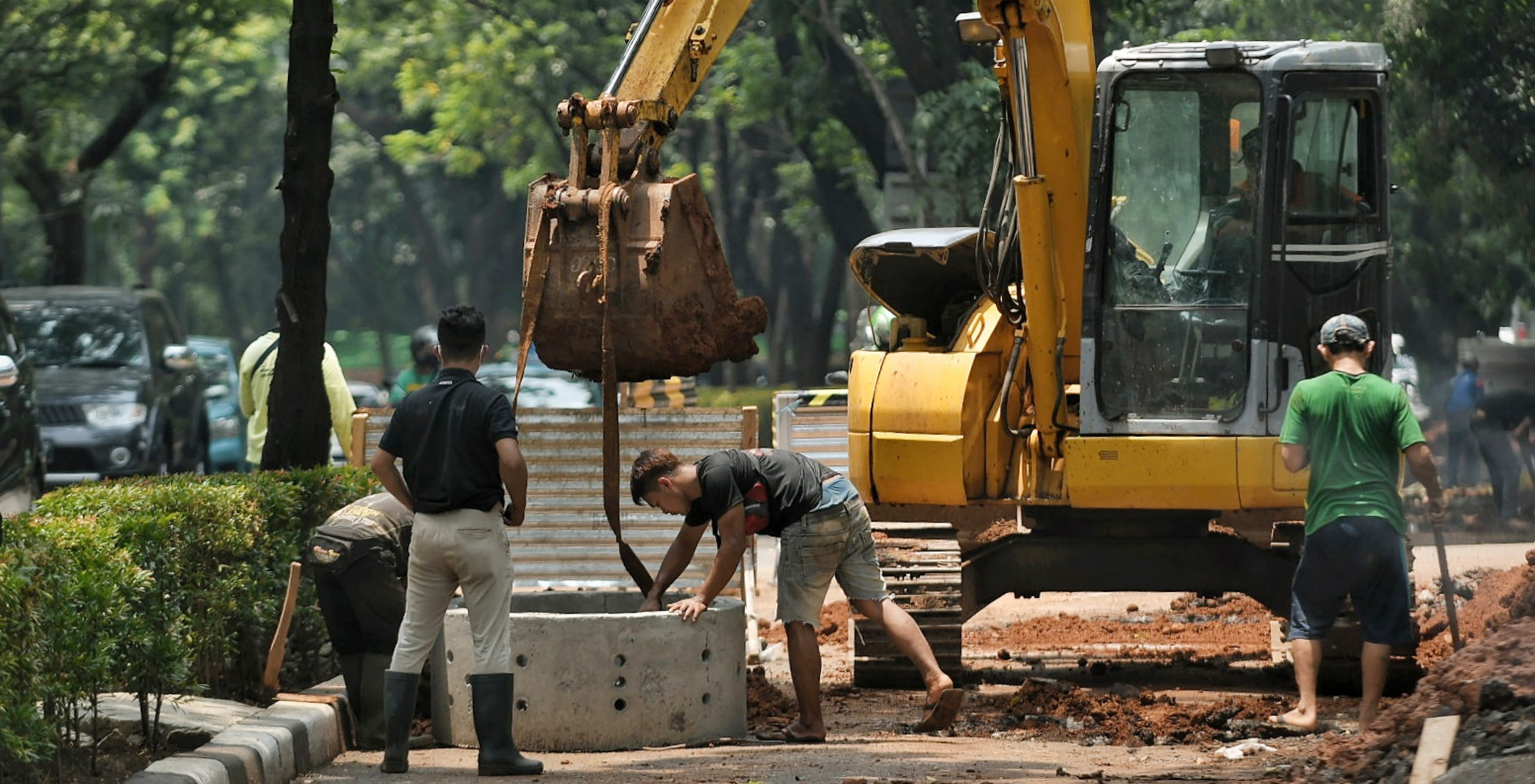 Pekerja menggunakan alat berat saat menyelesaikan pengerjaan sumur resapan.