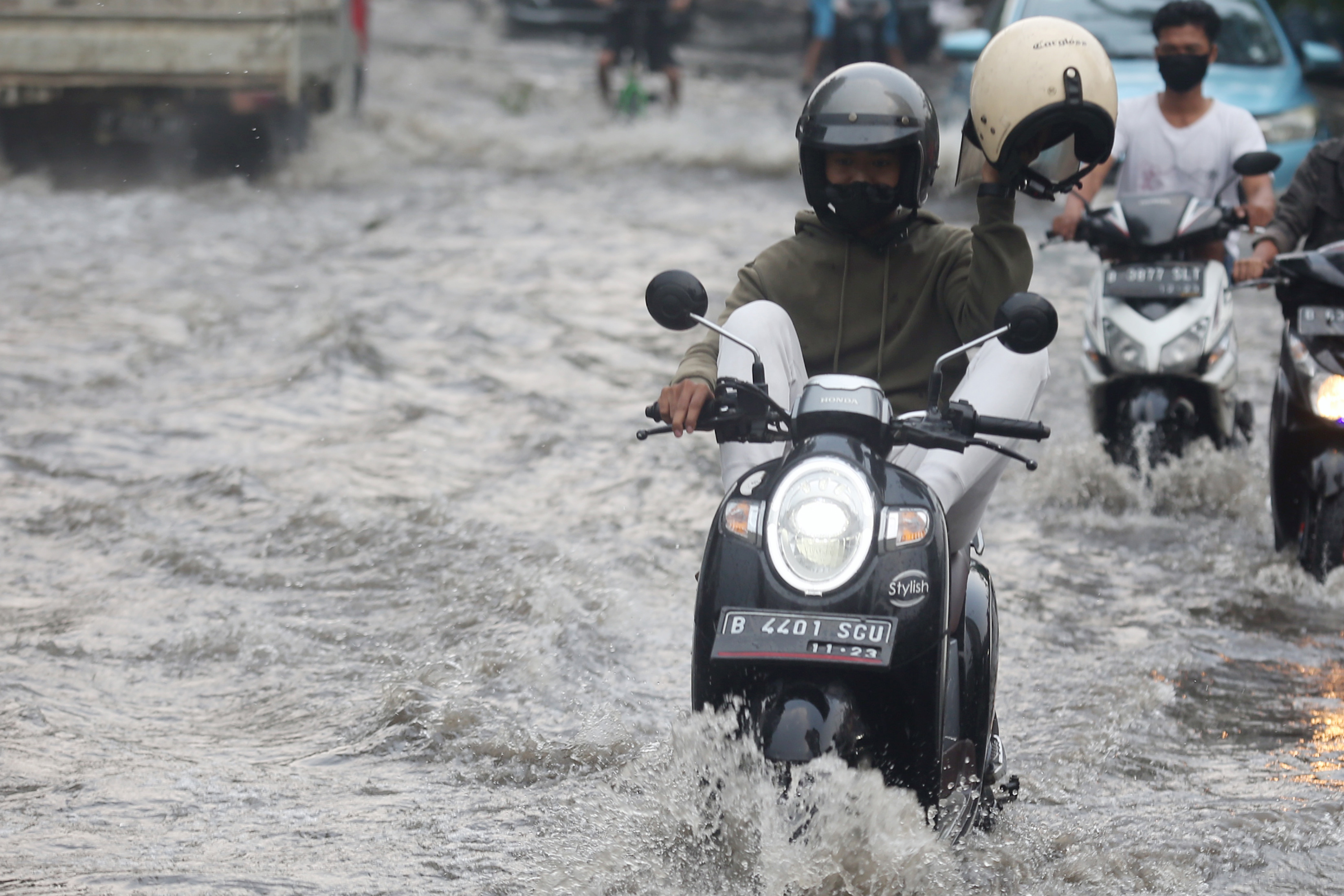 Pengendara motor menerabas genangan air