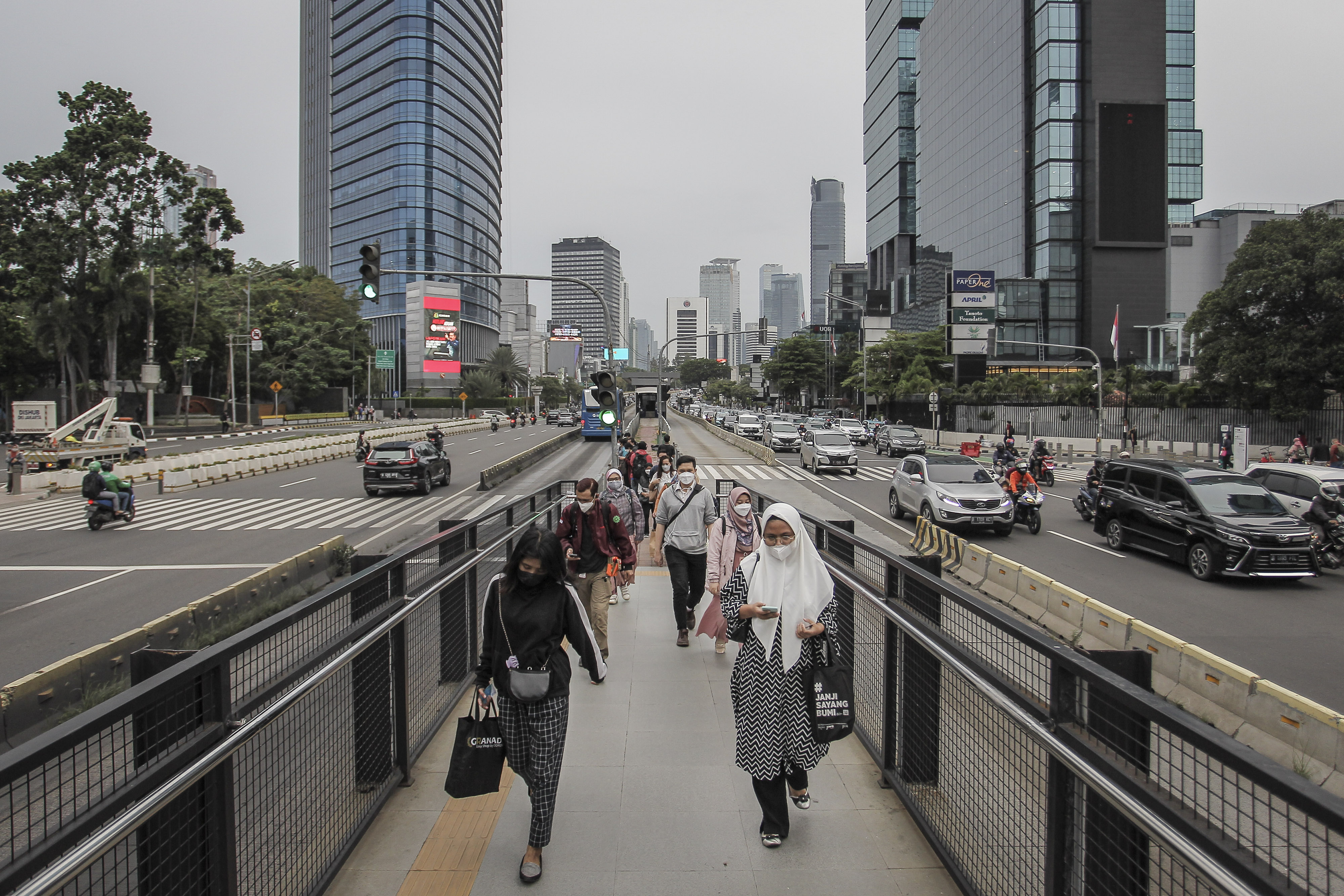 Warga berjalan menuju halte bus TransJakarta di Jalan Jenderal Sudirman, Jakarta, Senin (15/11/2021)