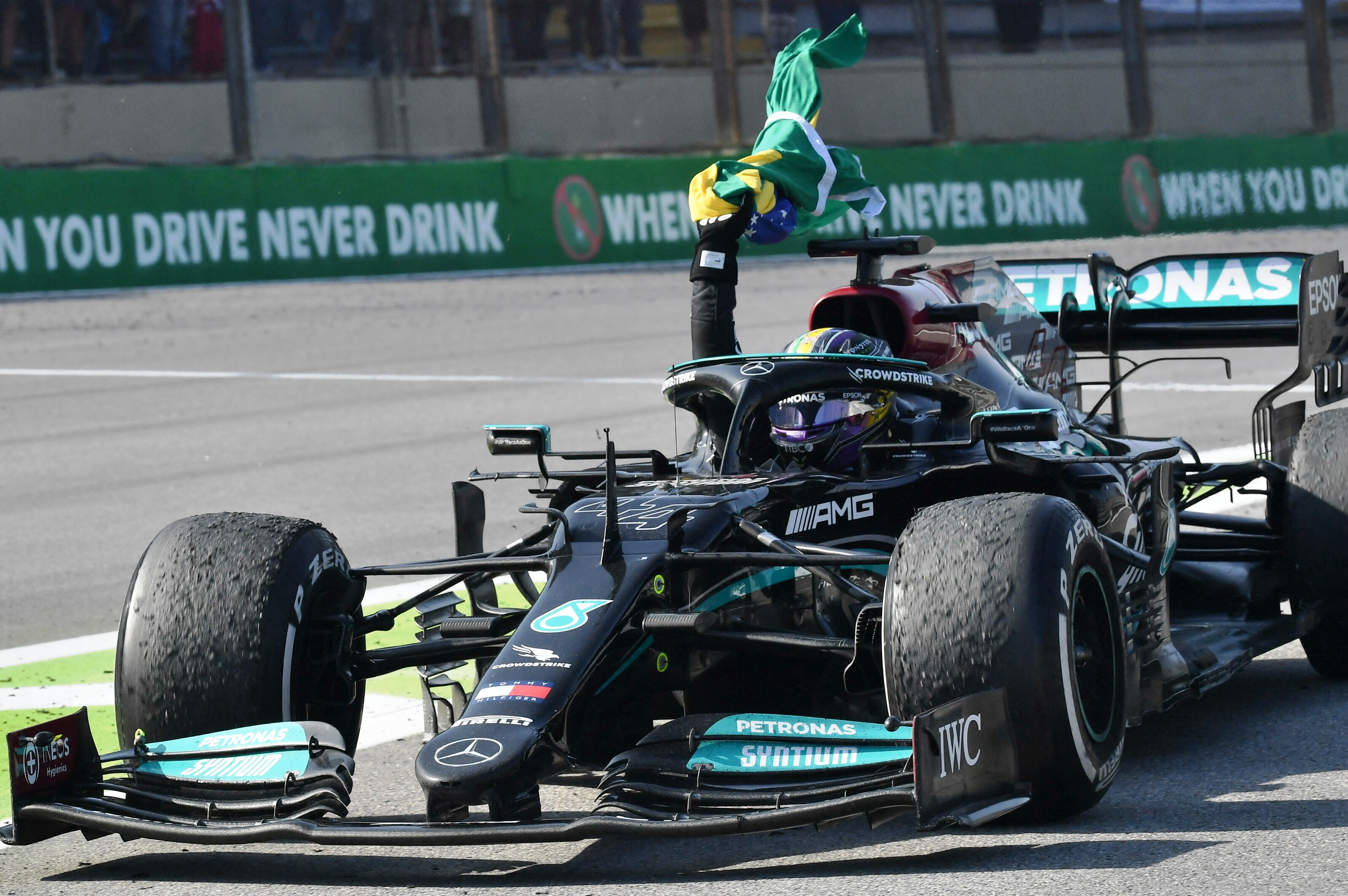 Pembalap Inggris dari tim Mercedes, Lewis Hamilton, melakukan selebrasi dengan mengibarkan bendera Brasil di Grand Prix Sao Paulo, Brasil. 