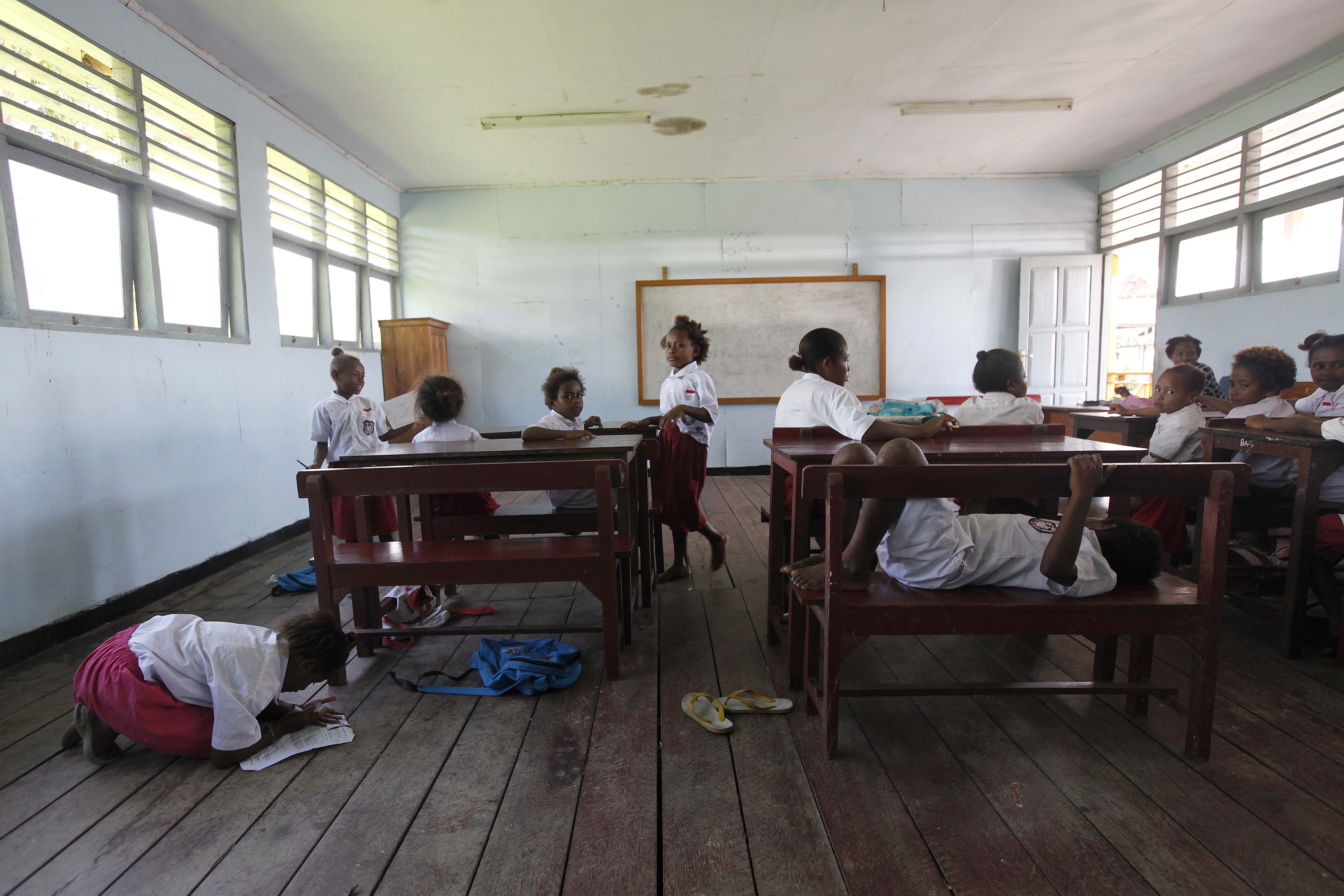 Anak murid mengerjakan tugas pelajaran di SD YPK Ifar Babrongko, Kampung Yoboi, Distrik Sentani, Kabupaten Jayapura, Papua.