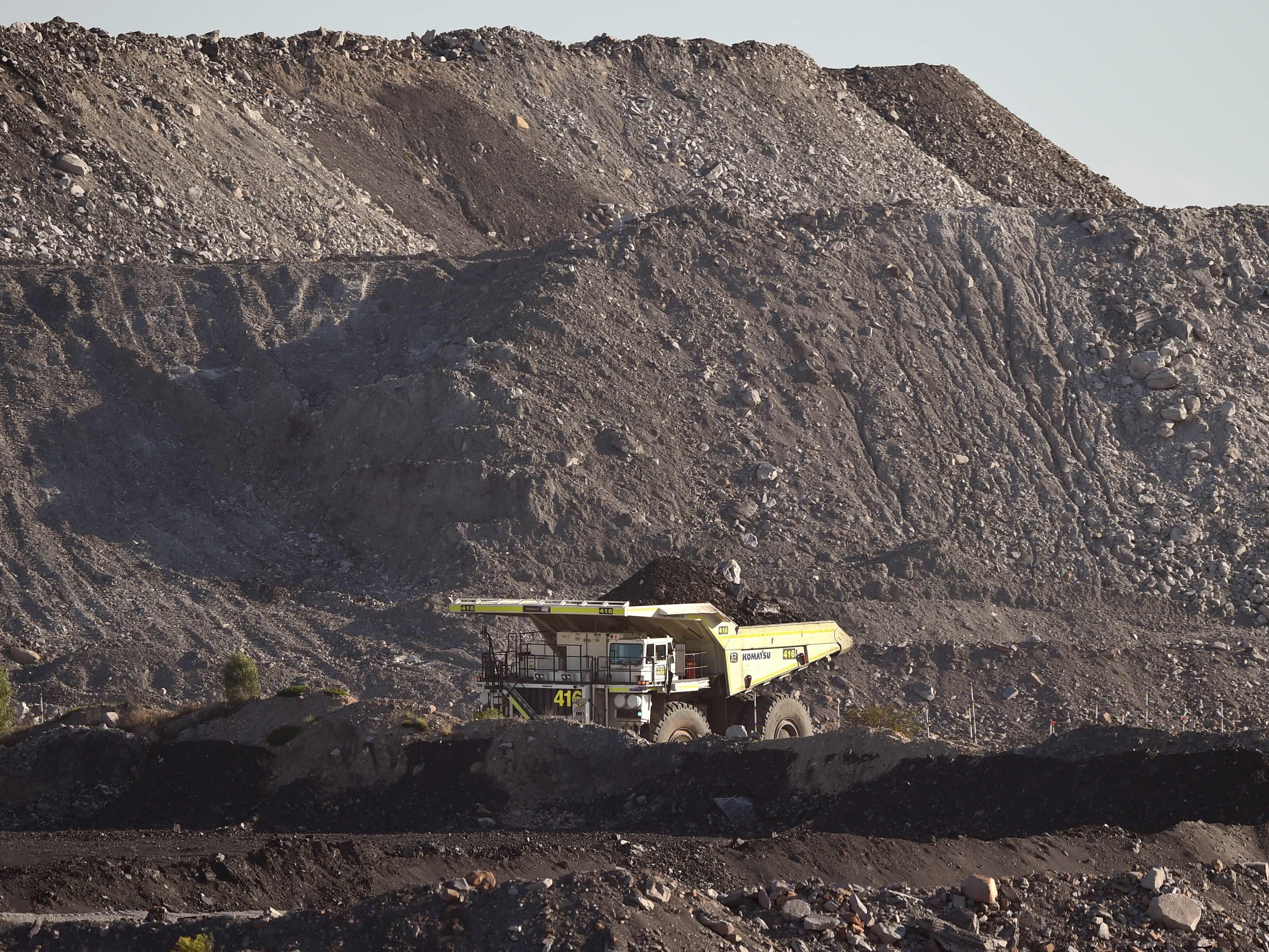 Truk besar mengemudi melalui tambang batu bara terbuka di Singleton di Hunter Valley di utara Sydney.
