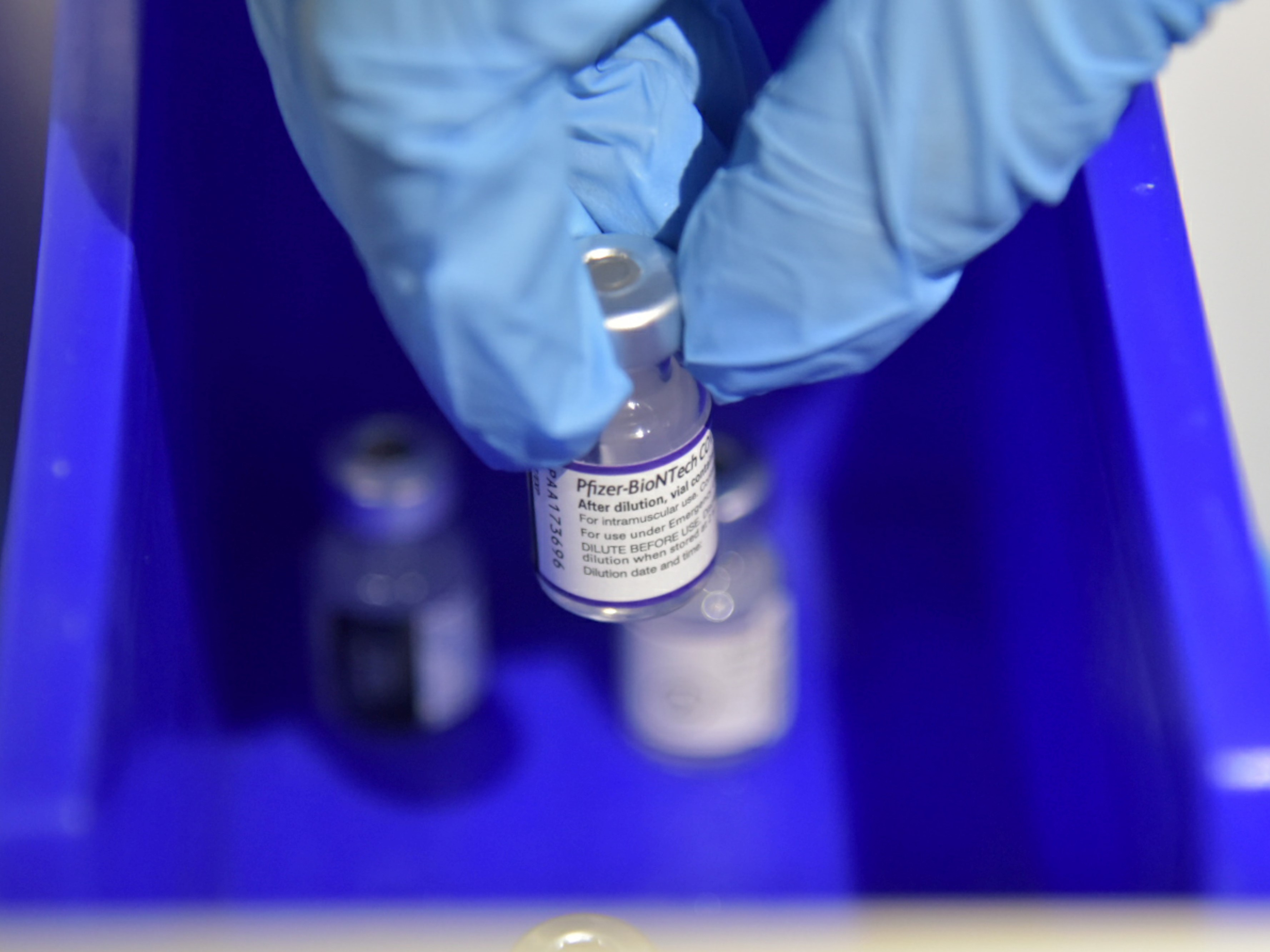 Petugas kesehatan mengambil botol berisi vaksin covid-19 jenis Pfizer yang akan disuntikkan kepada warga saat pelaksanaan vaksinasi.