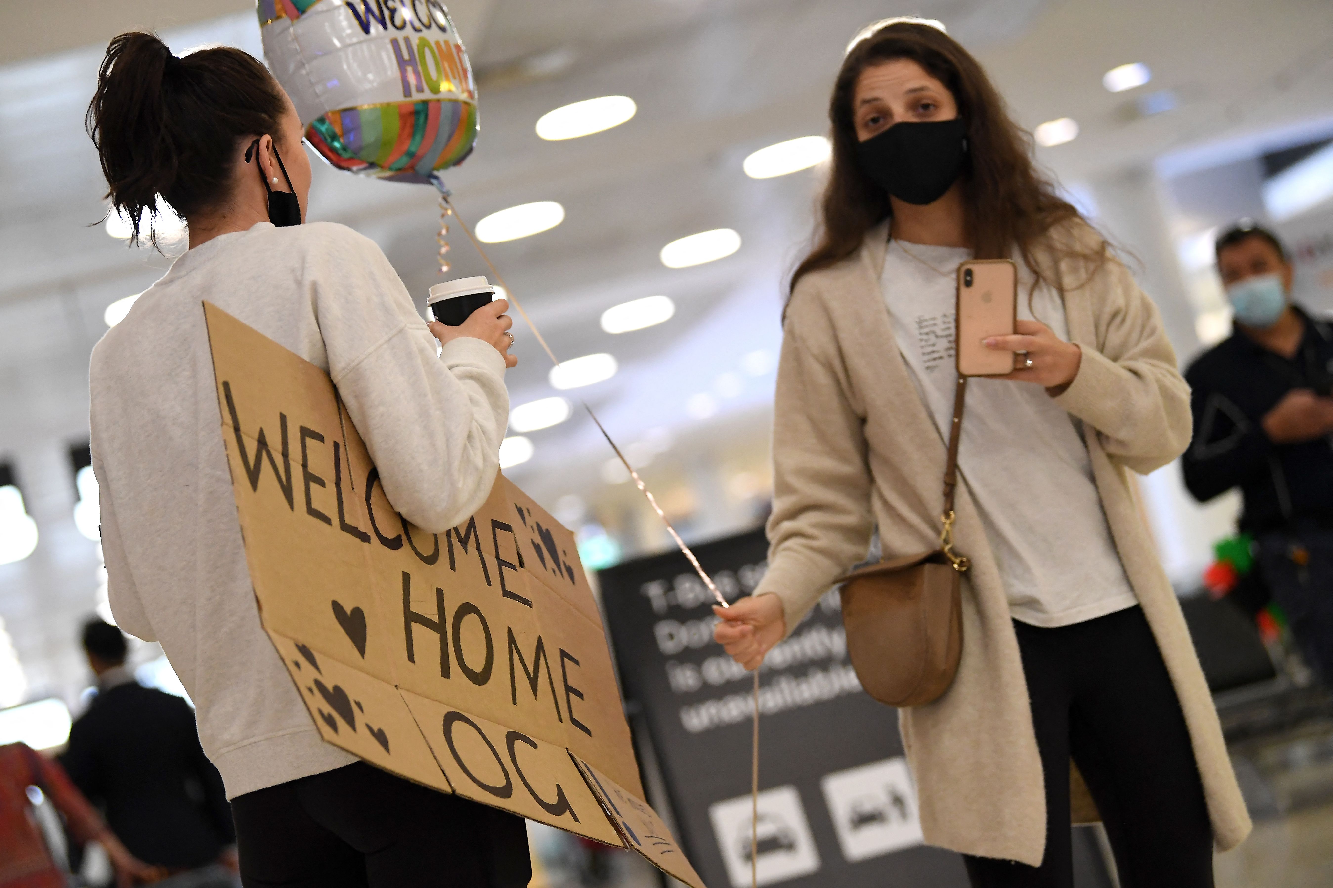 Anggota keluarga menunggu orang yang mereka cintai di ruang kedatangan di bandara Internasional Sydney, Senin (1/11) setalah pembatasan dilo