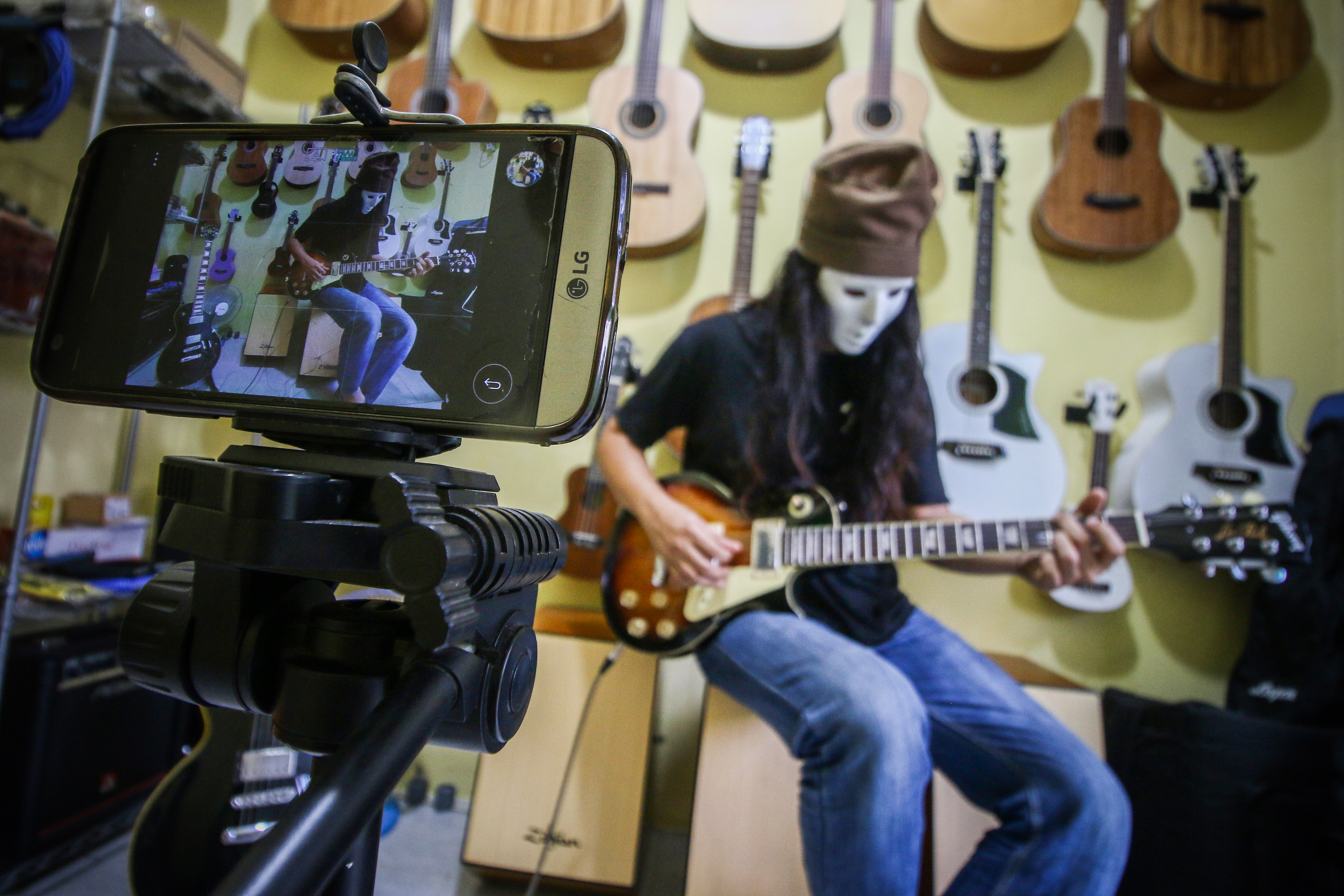 Pedagang gitar rumahan memainkan gitar yang akan dijual secara daring di Ciledug, Tangerang, Banten.