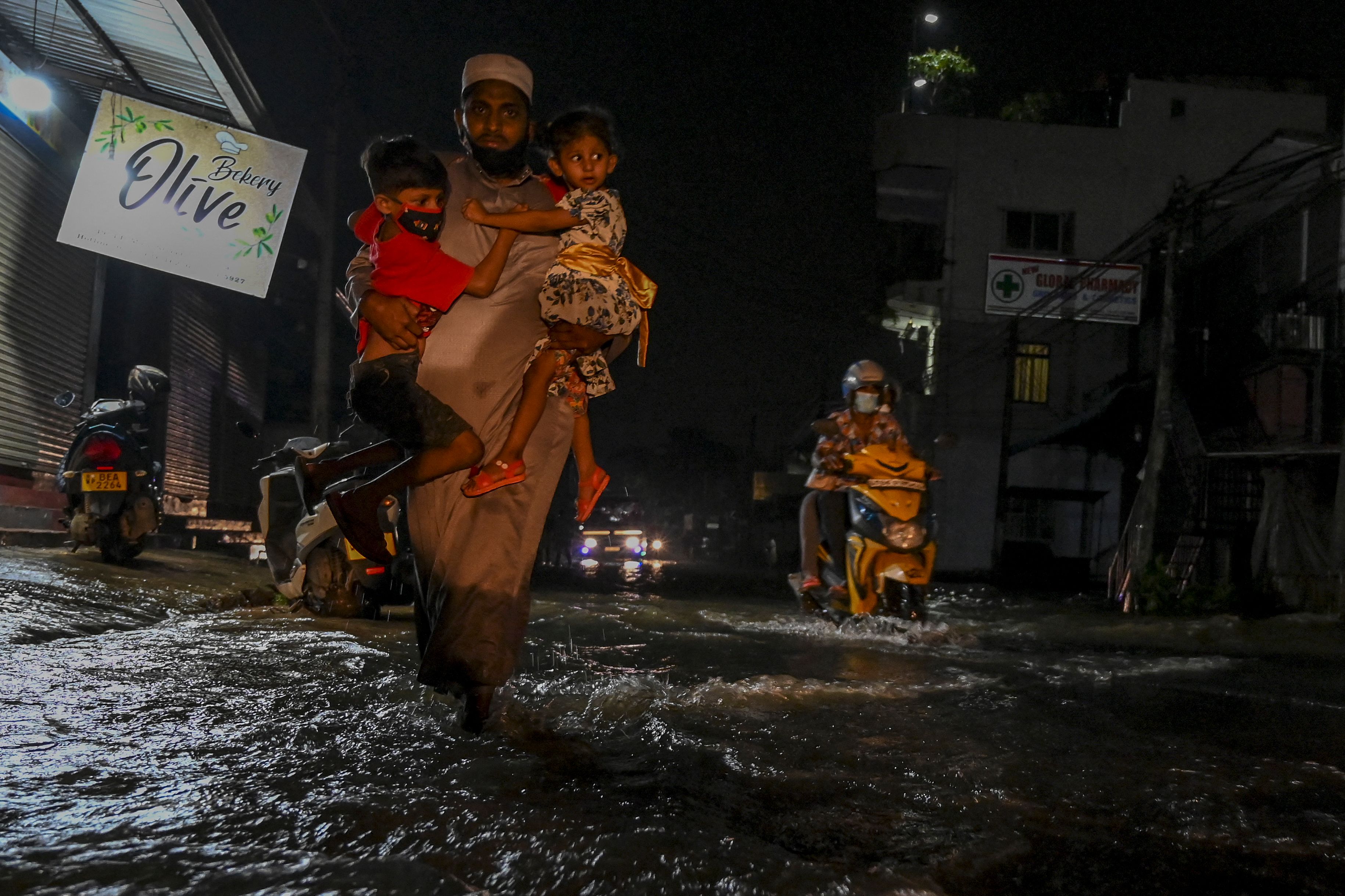 Warga berjalan melintasi banjir di Kota Malwana, Sri Lanka.
