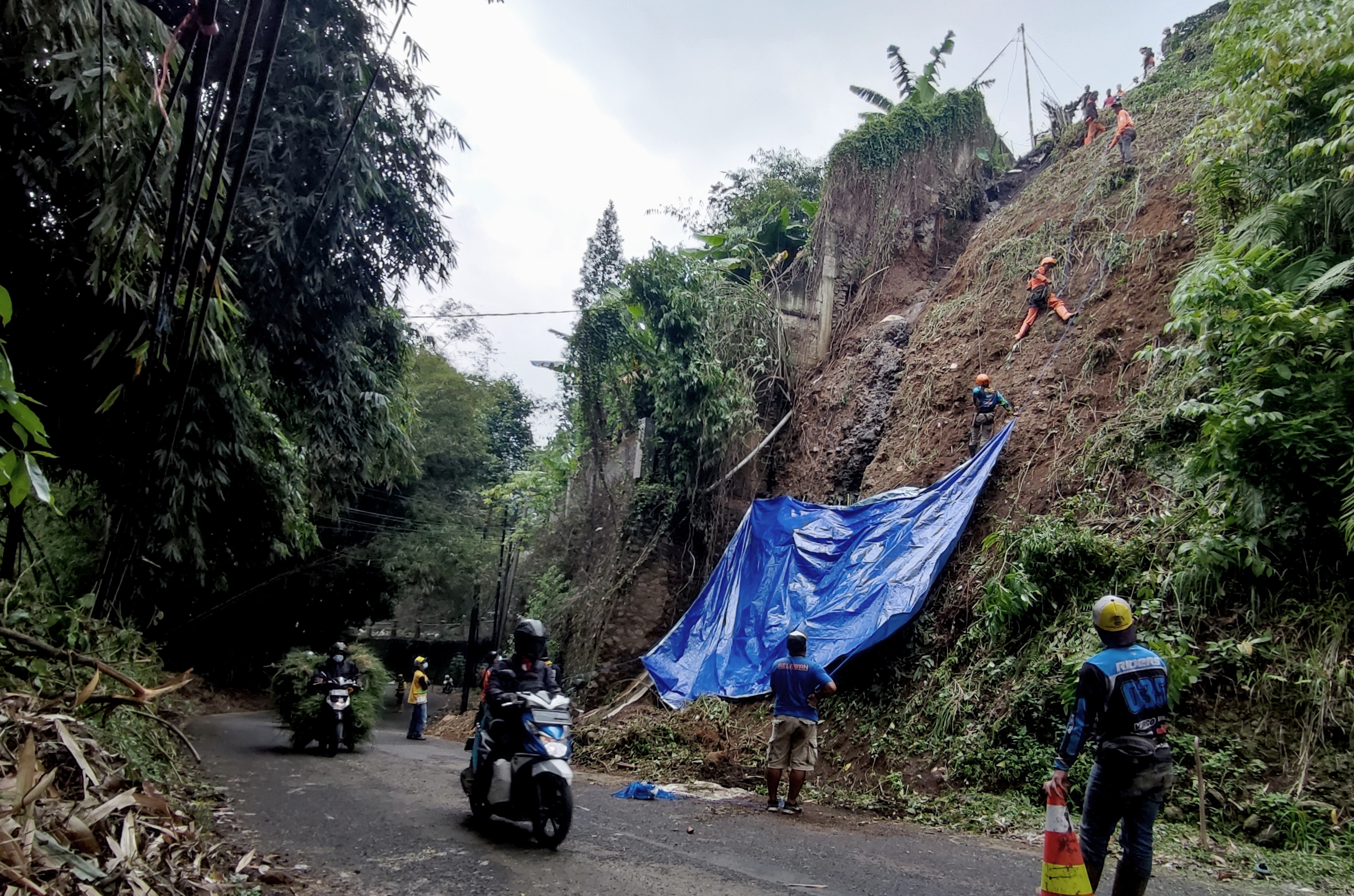 Petugas memasang terpal untuk menahan material dari tebing yang longsor di  Kampung Keramat, Desa Cikahuripan Kecamatan Lembang, Jawa Barat.