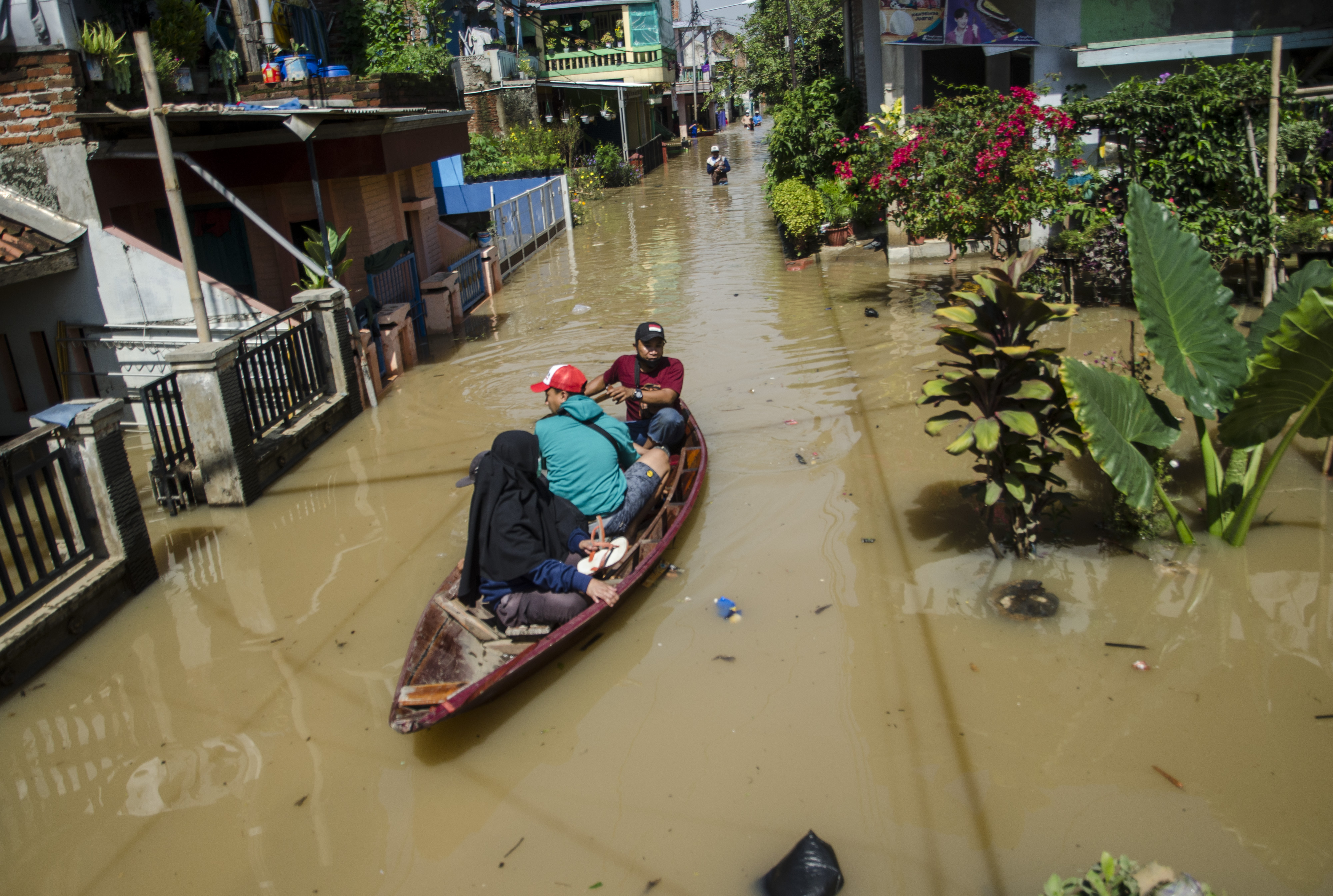 Warga menaiki perahu untuk melintasi genangan banjir di Dayeuhkolot, Kabupaten Bandung, Jawa Barat, Minggu (3/11/2021).