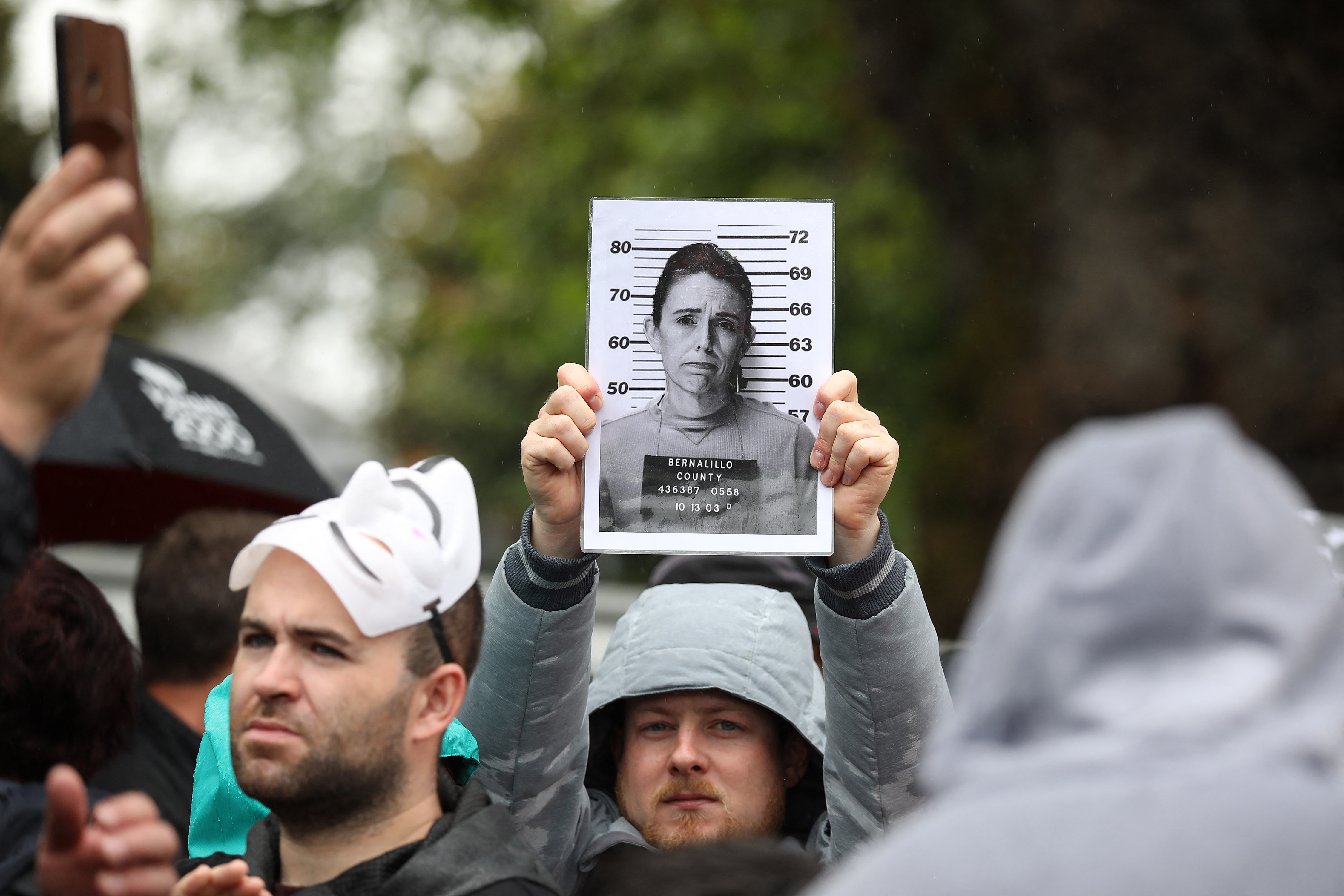 Sekelompok orang berunjuk rasa anti-lockdown dengan menunjukkan foto PM Selandia Baru Jacinda Ardern di Christchurch, Sabtu (13/11). 