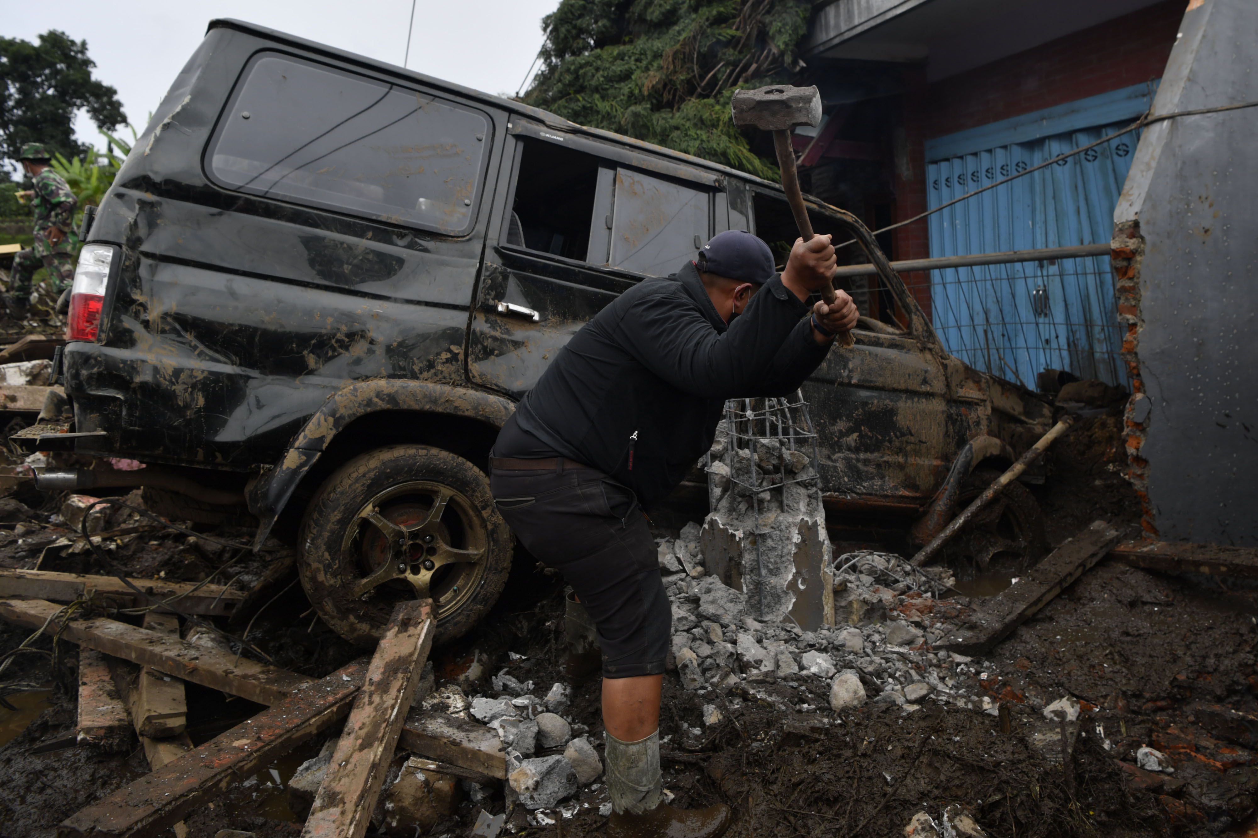 Seorang relawan mengamankan sebuah mobil yang terperosok akibat banjir bandang di Bulukerto, Kota Batu, Jawa Timur, Jumat (5/11/2021)