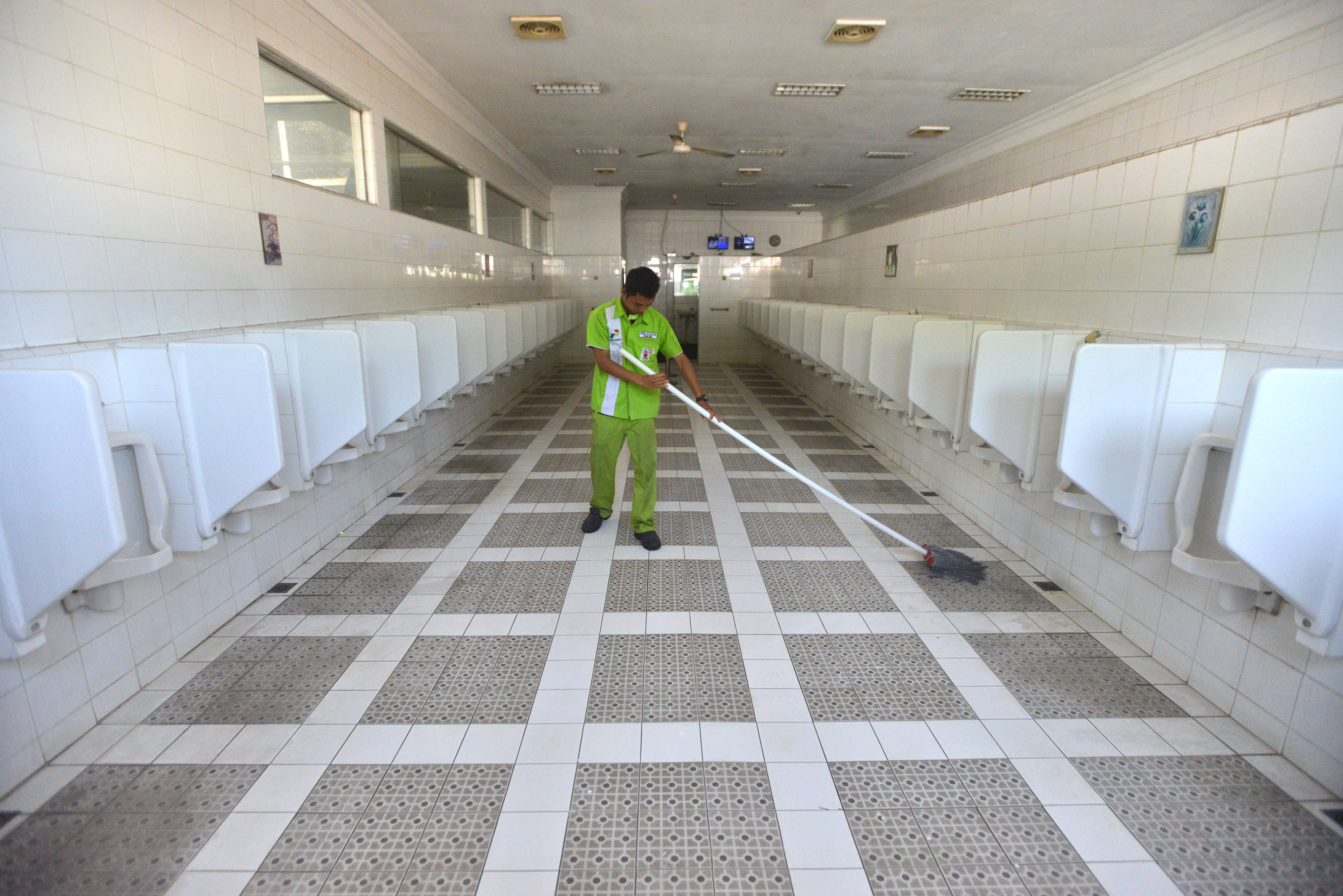 Petugas membersihkan lantai toilet untuk para pemudik di SPBU 4452109 di Jalan Raya Dampyak, Tegal, Jawa Tengah, beberapa waktu lalu.