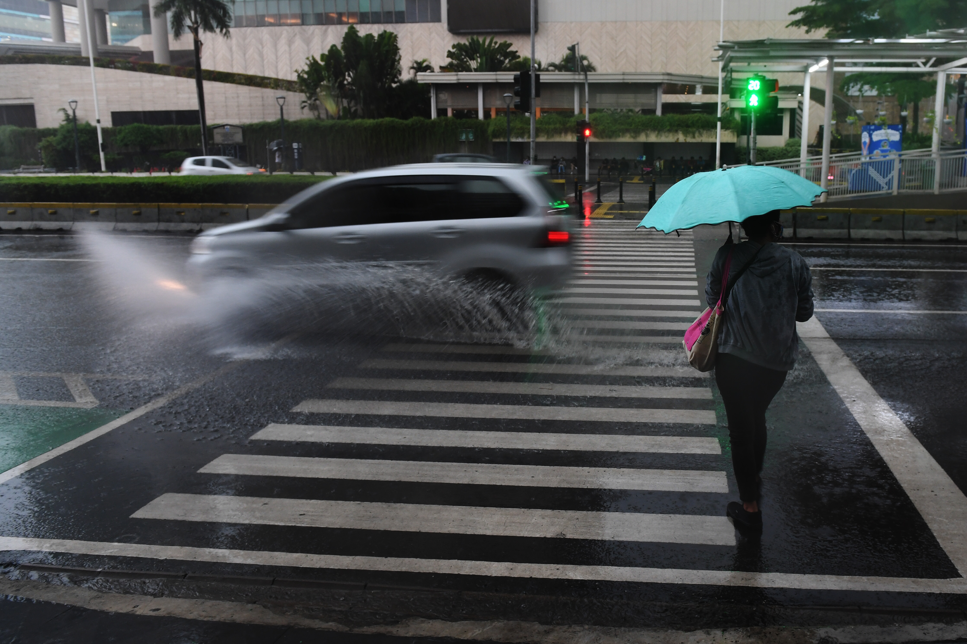 Warga berjalan sambil membawa payung saat hujan di kawasan Bundaran Hotel Indonesia, Jakarta.