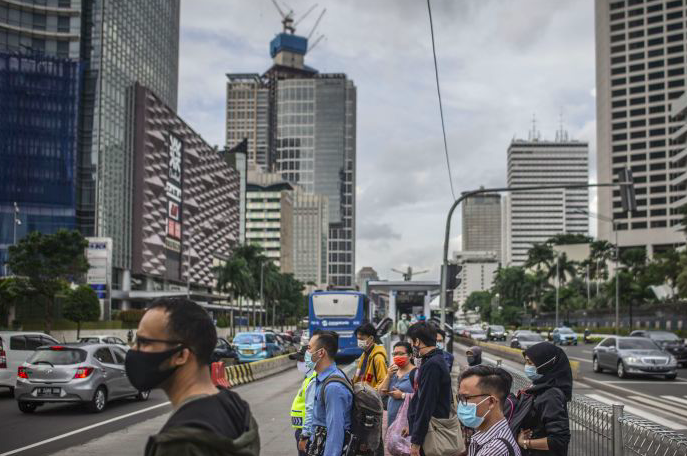 Warga bersiap menyeberang Jalan Jenderal Sudirman di Jakarta, Kamis (17/12/2020).