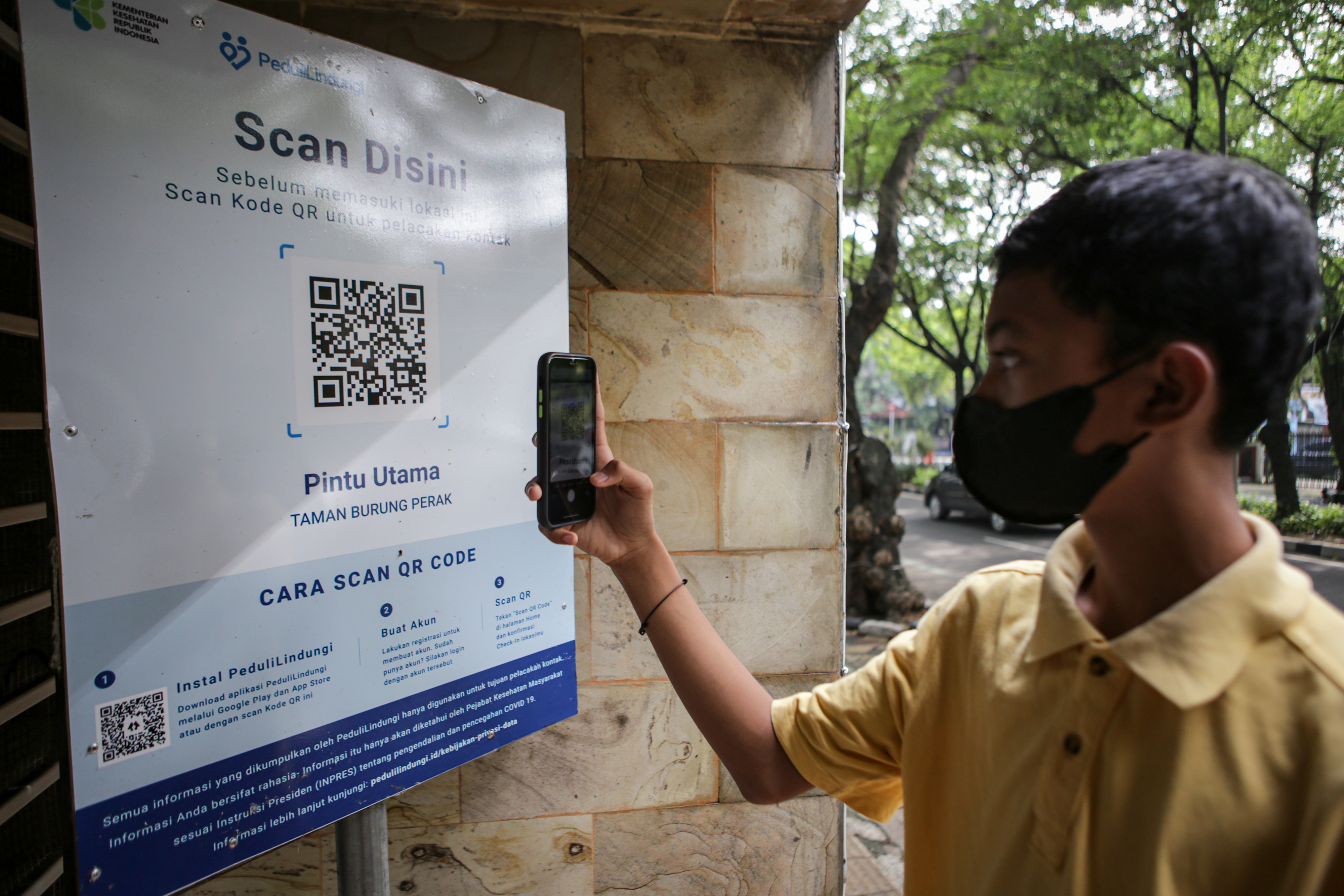 Warga memindai kode batang aplikasi PeduliLindungi di Taman di Kota Tangerang, Banten