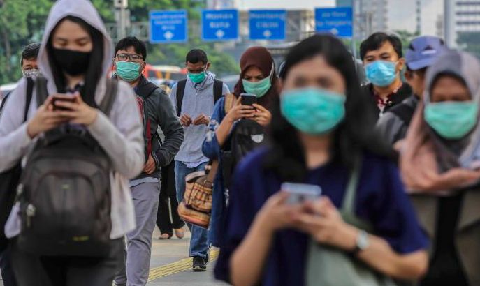 Pekerja menggunakan masker pelindung saat melewati trotoar menuju kantornya di kawasan Sudirman, Jakarta.