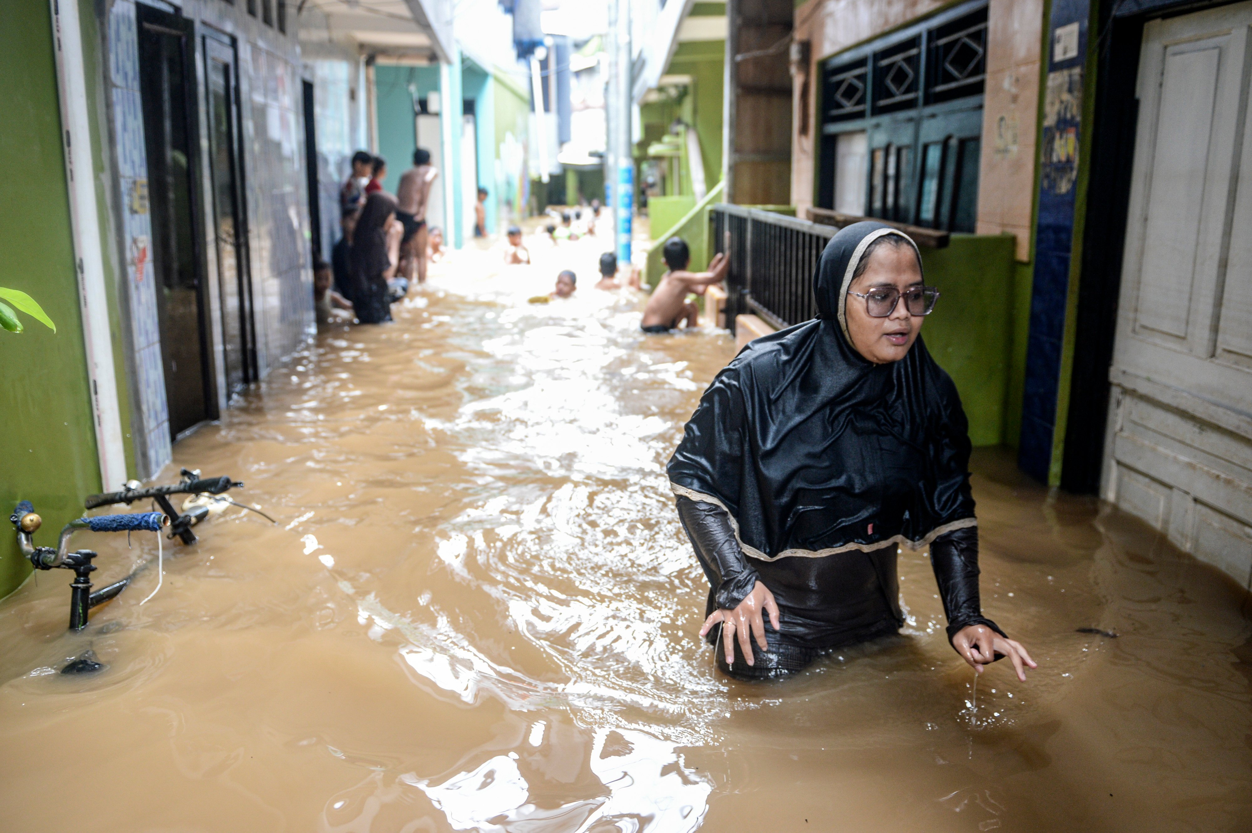 Warga melintasi banjir yang merendam kawasan Kebon Pala, Kampung Melayu, Jatinegara, Jakarta Timur.