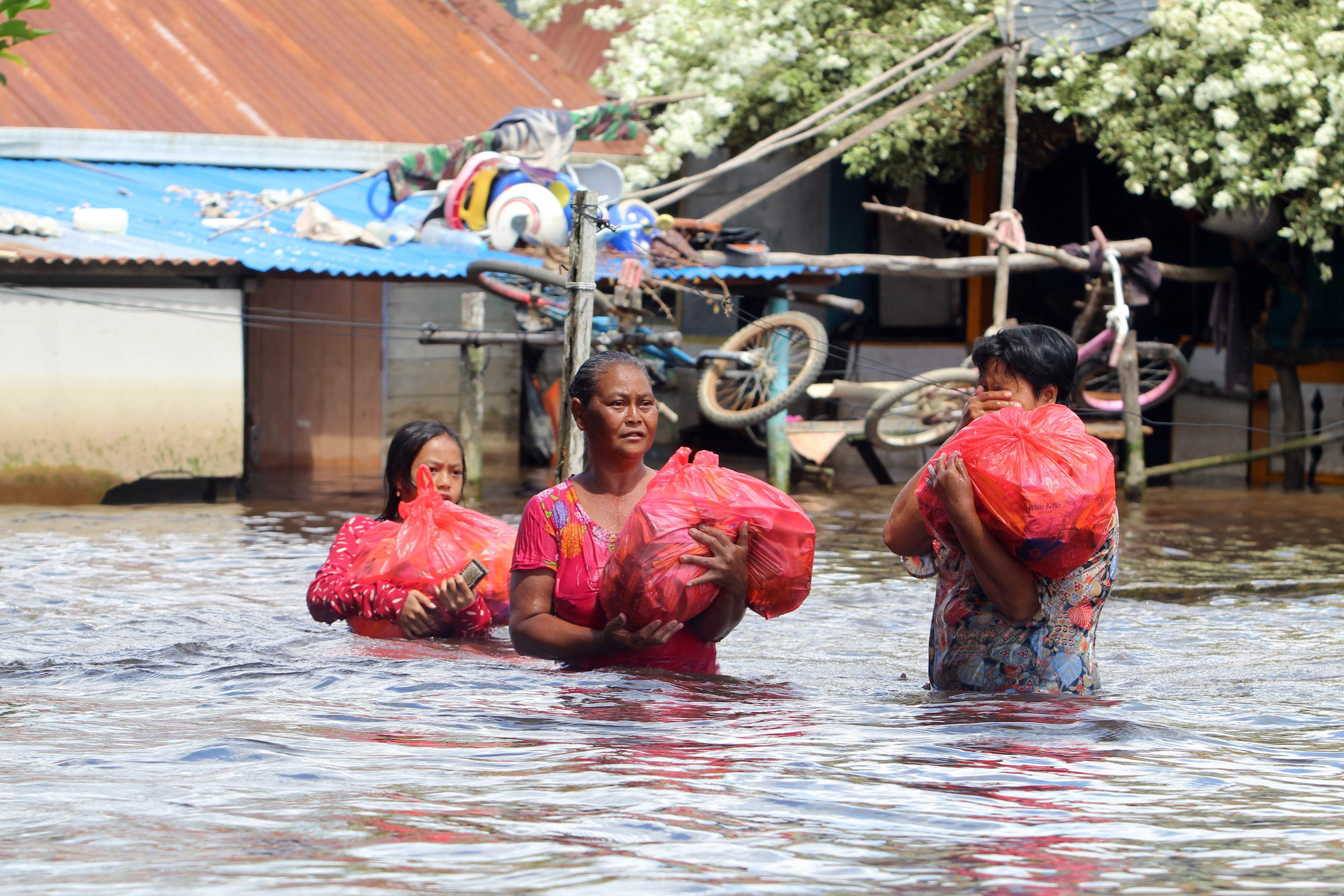 Sejumlah warga membawa bungkusan sembako saat melintasi permukiman masyarakat di tepian Sungai Kapuas, Sintang, Kalimantan Barat