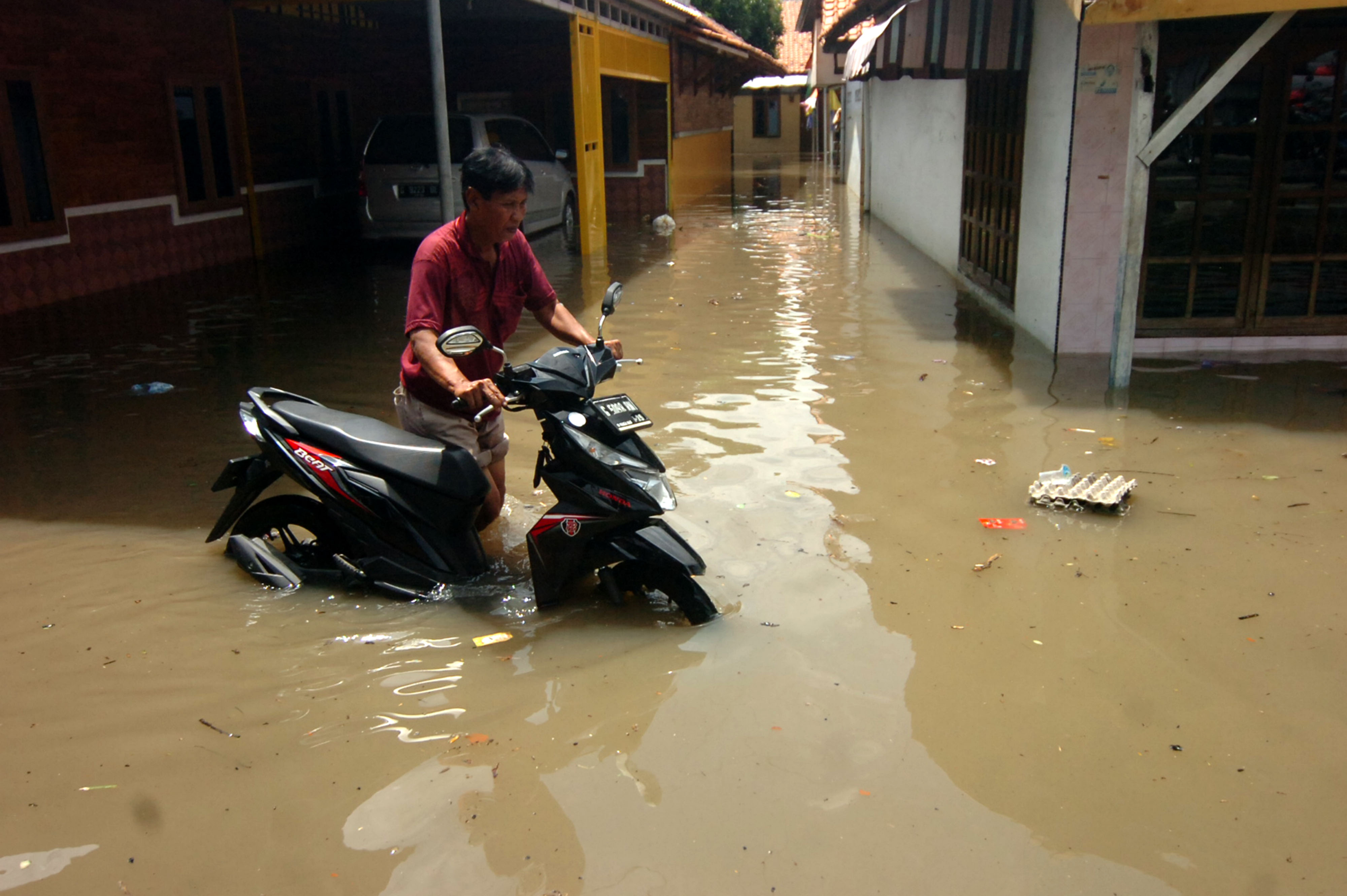  Warga menyelamatkan sepeda motornya yang terendam banjir di Kelurahan Pesurungan, Tegal, Jawa Tengah, Selasa (23/11).