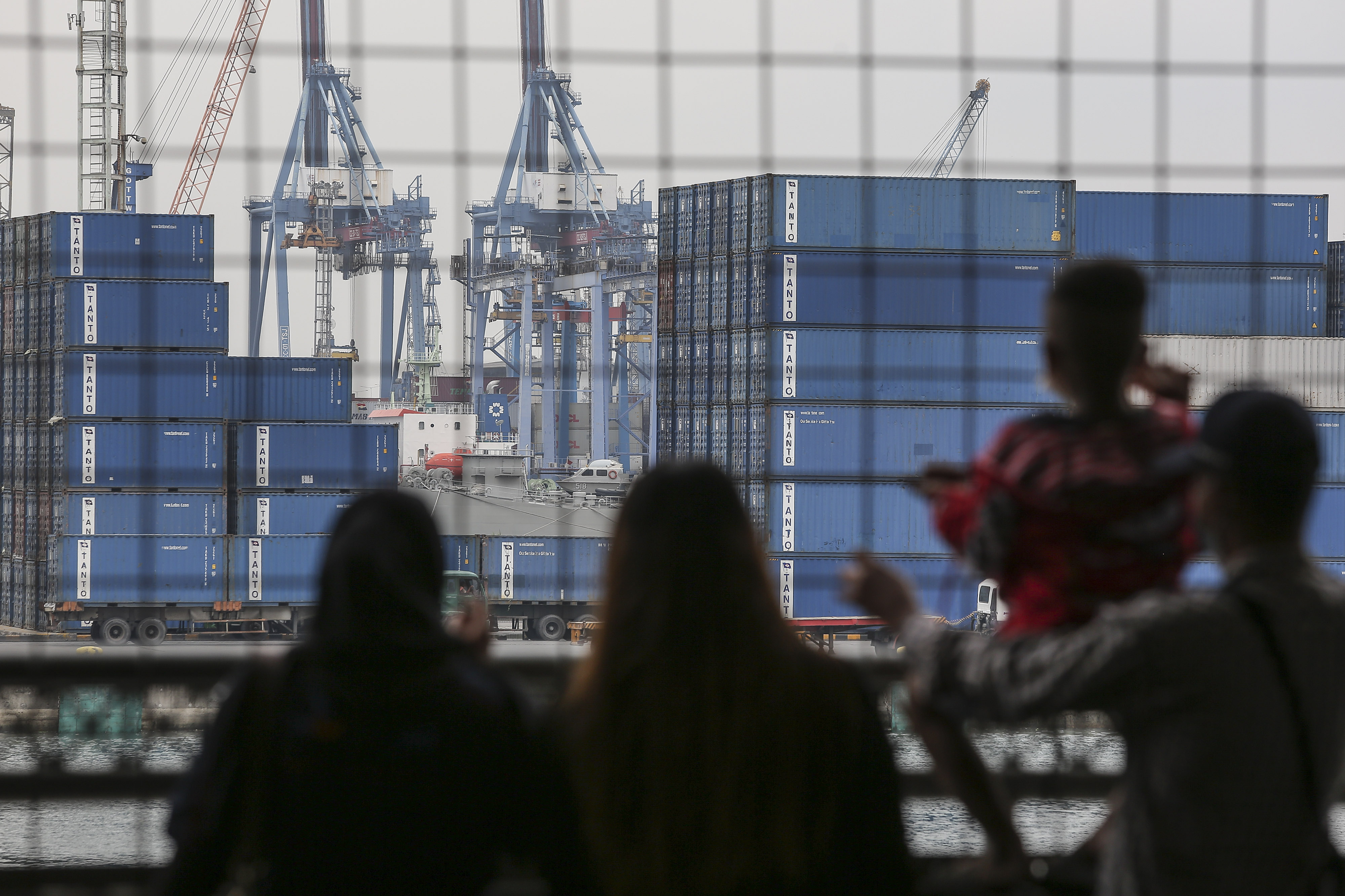 Calon penumpang mengamati suasana bongkar muat peti kemas di Pelabuhan Tanjung Priok, Jakarta, Senin (15/11/2021)