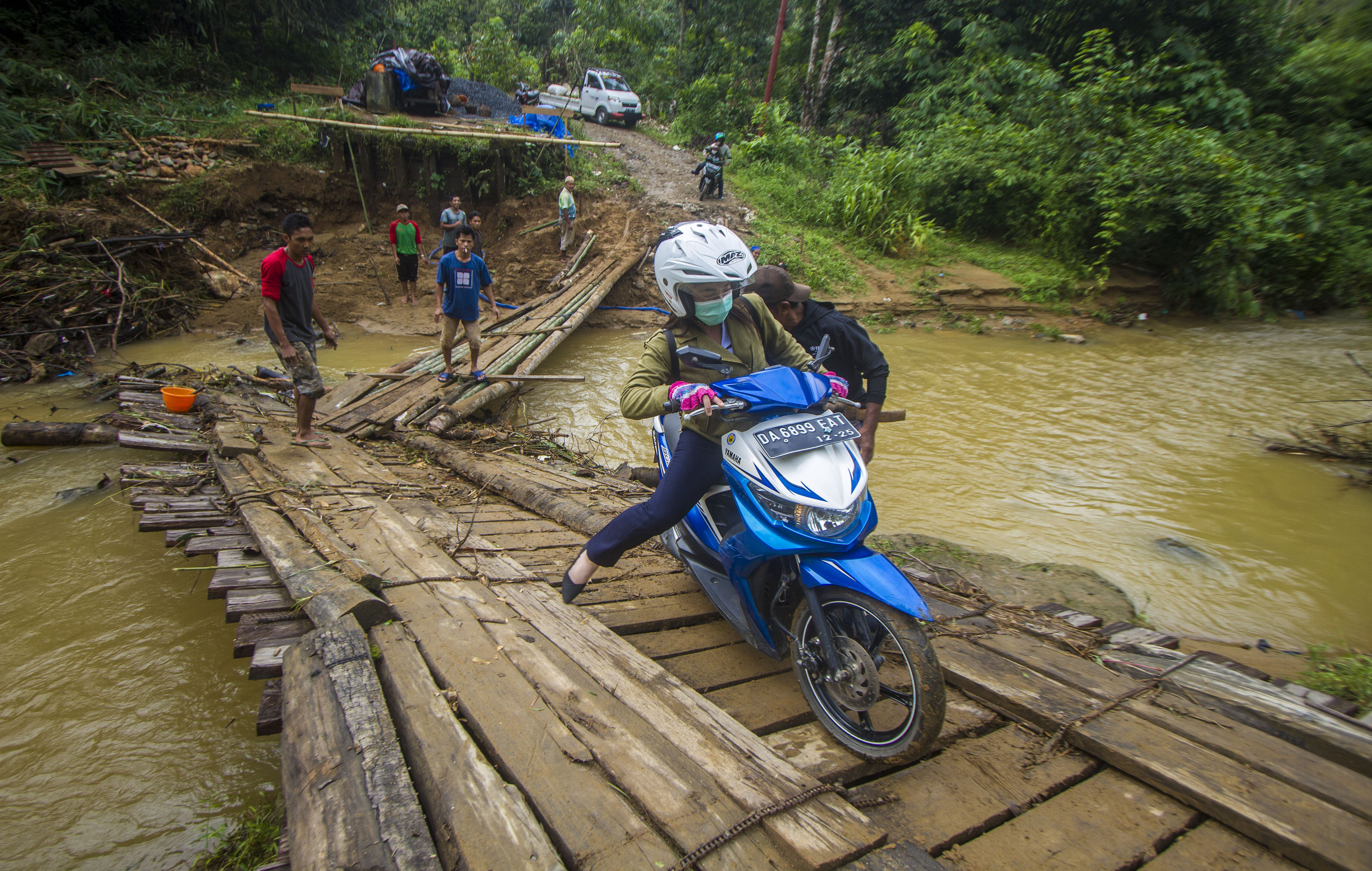  Pengendara motor tergelincir saat melintasi jembatan darurat di Desa Murung B, Kecamatan Hantakan, Kalimantan Selatan, Senin (8/11/2021)