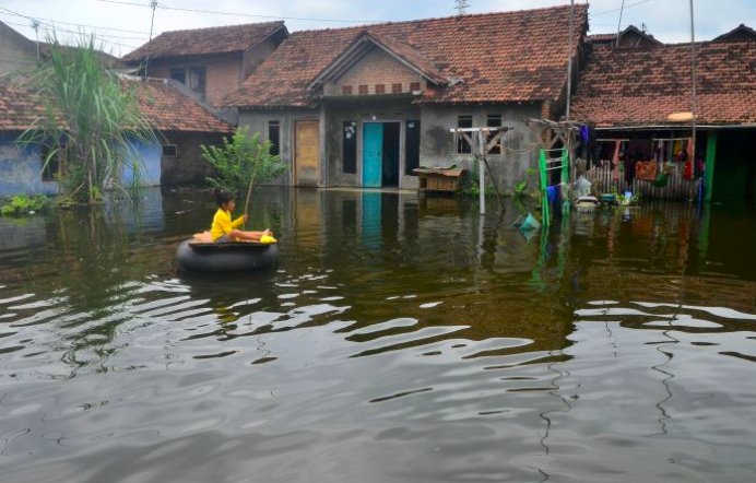 Seorang anak bermain di halaman rumah yang tergenang banjir di Dukuh Tanggulangin, Jati, Kudus, Jawa Tengah, kemarin.