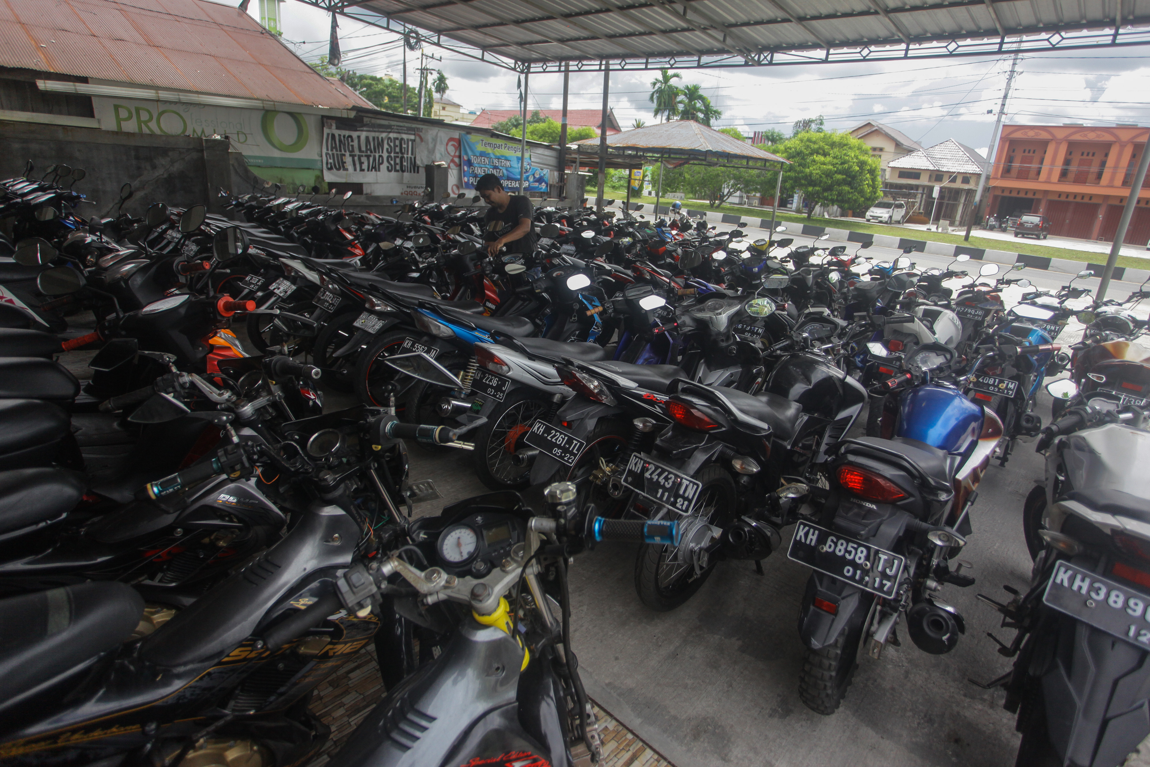 Pedagang membersihkan sepeda motor bekas yang dijual di Jalan George Obos, Palangkaraya, Kalimantan Tengah.