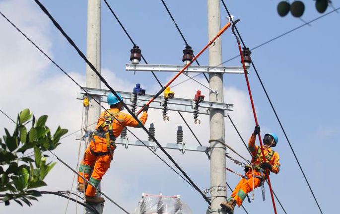 Pekerja PLN melakukan perawatan pada jaringan listrik dalam keadaan masih bertegangan di Desa Ngasem, Kediri, Jawa Timur, Jumat (23/7/2021).
