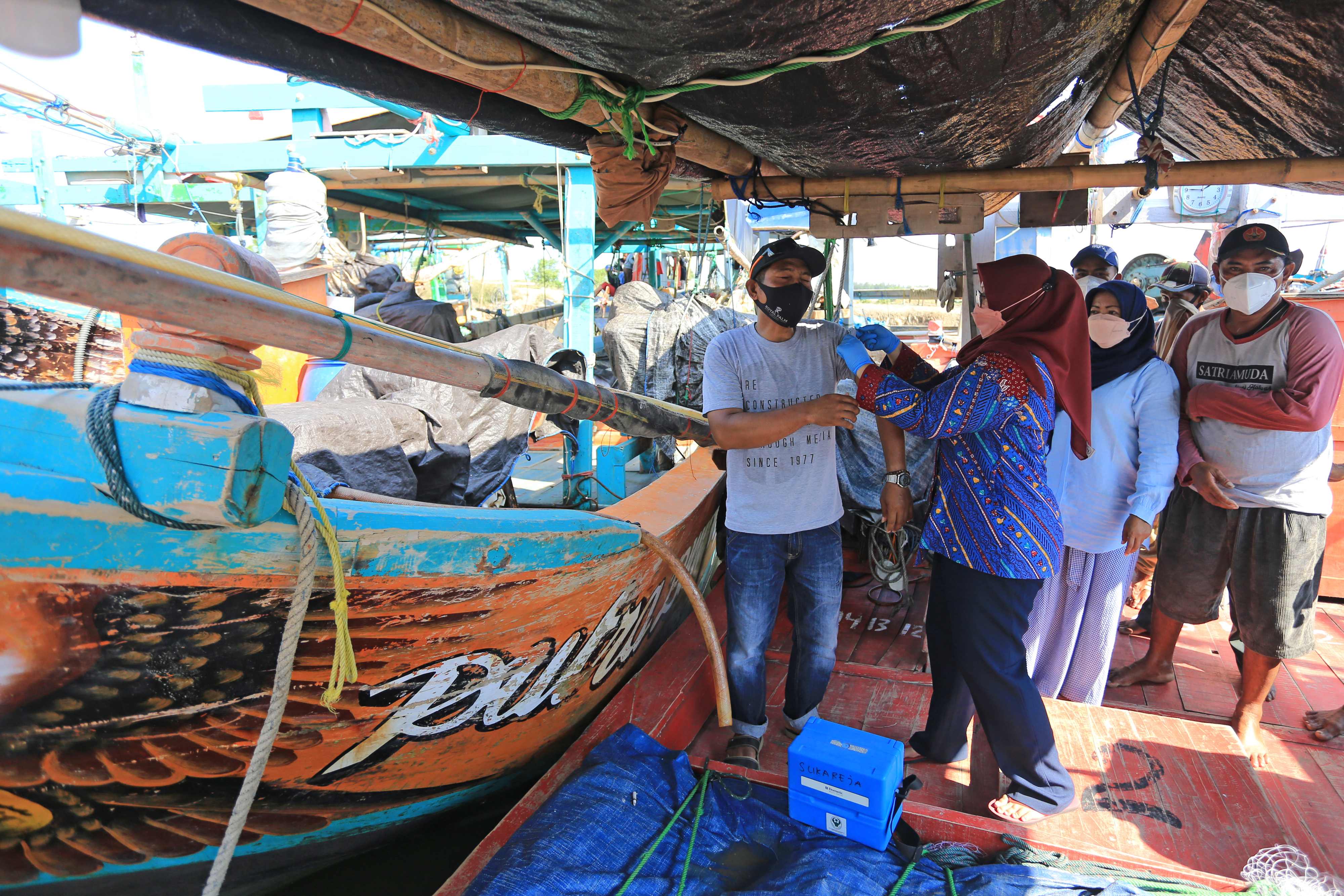  Petugas Puskesmas menyuntikkan vaksin pada nelayan di tempat pelelangan ikan Majakerta, Balongan, Indramayu, Jumat (22/10/2021).