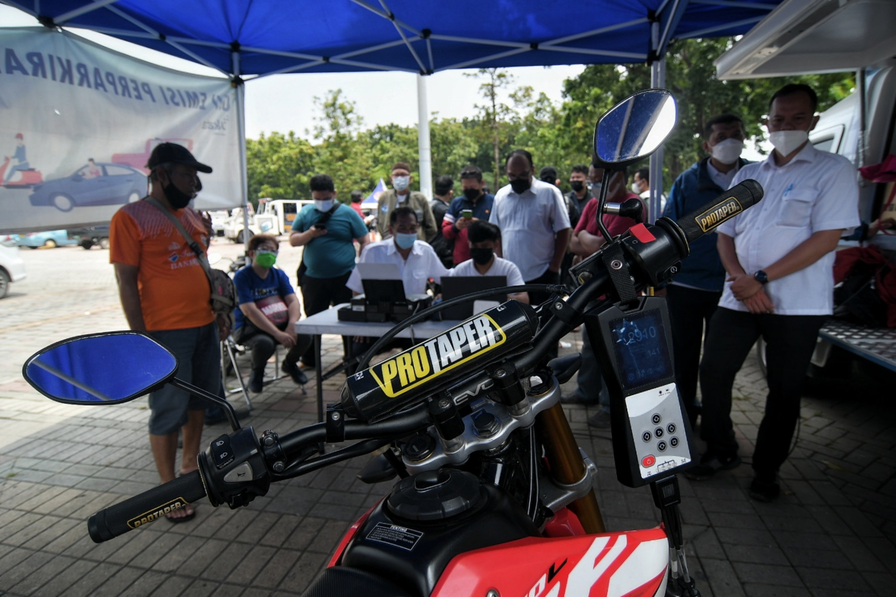 Warga saat menunggu kendaraannya dilakukan uji emisi gas buang kendaraan di Lapangan Parkir IRTI Monas, Jakarta, Rabu (3/11).