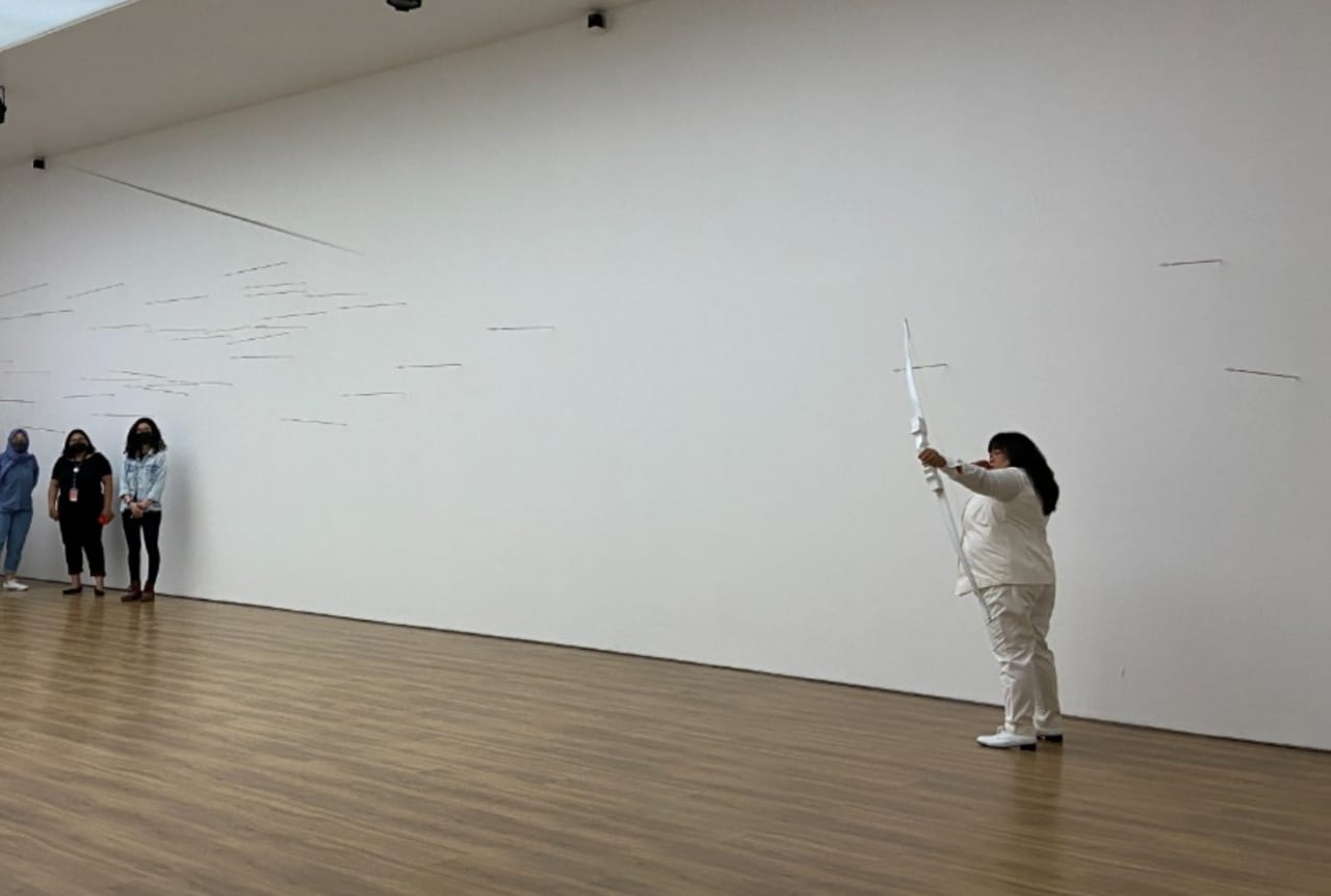 Melati Suryodarmo membidikkan panah dalam pertunjukan Transaction of Hollow di Museum Macan, Jakarta, Sabtu (6/11).