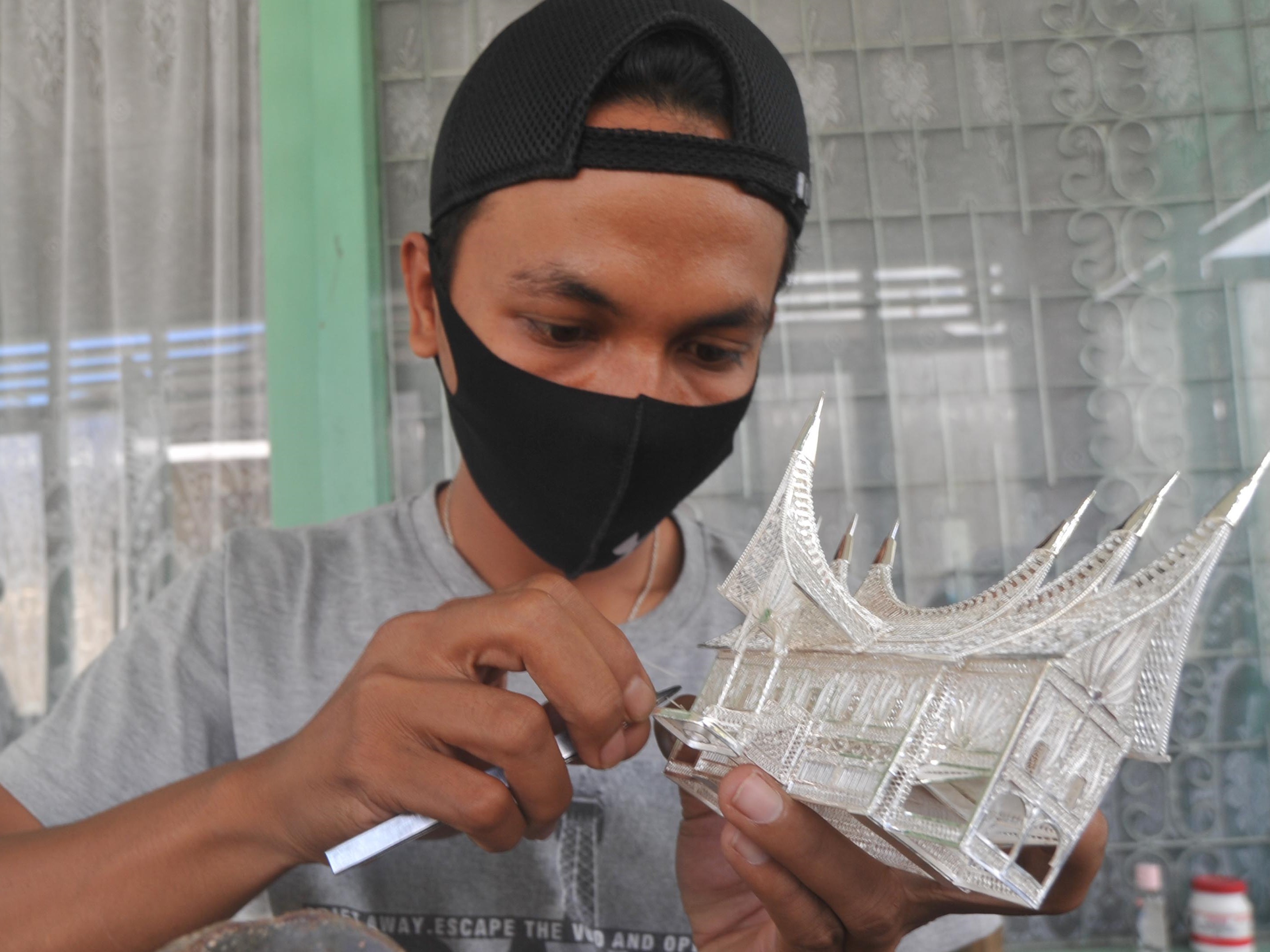 Seorang perajin perak menyelesaikan pesanan miniatur Rumah Gadang di Nagari Koto Gadang, Kabupaten Agam, Sumatra Barat.