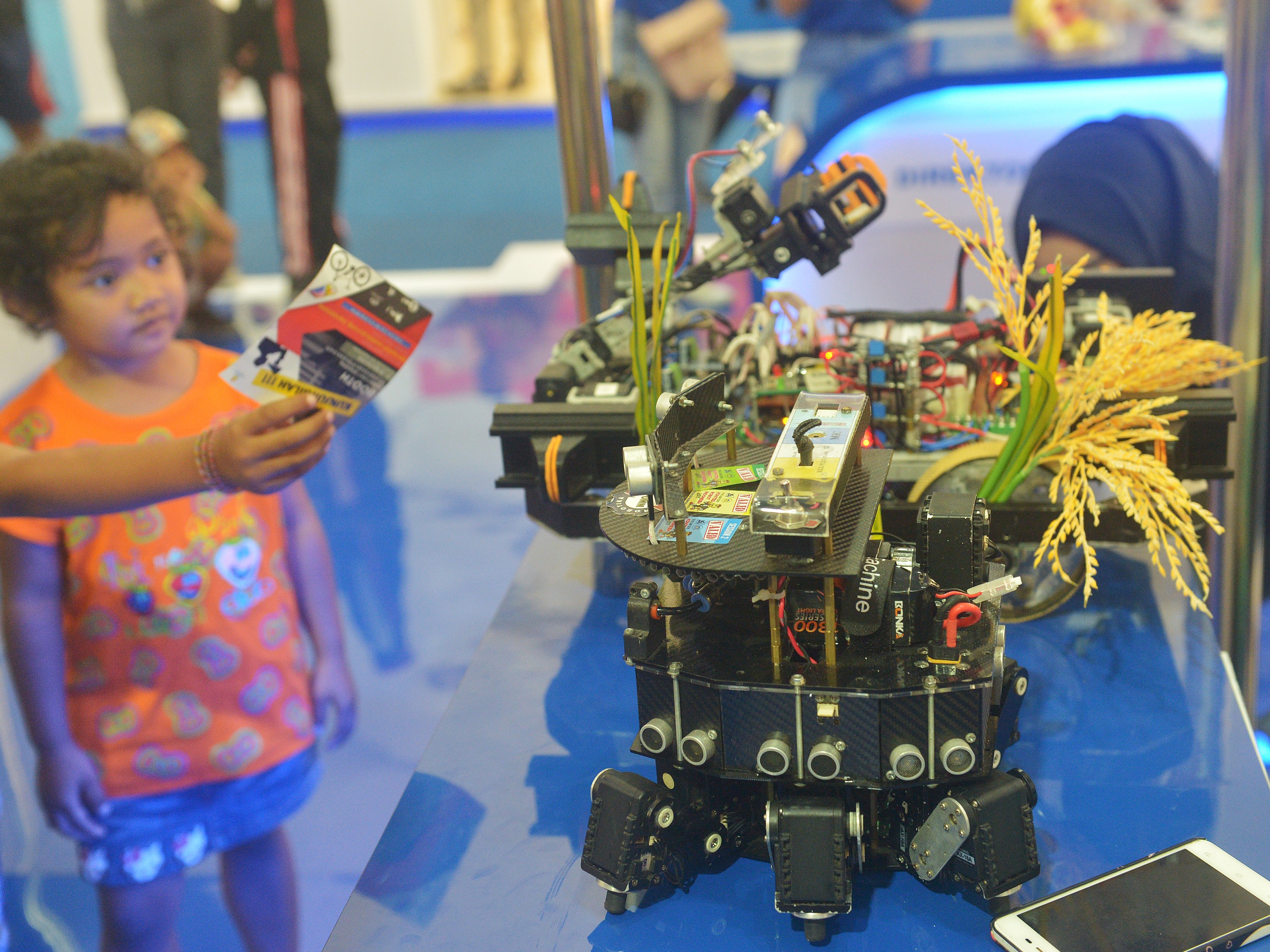Seorang anak melihat robot penanam padi dalam Ritech Expo 2019. 