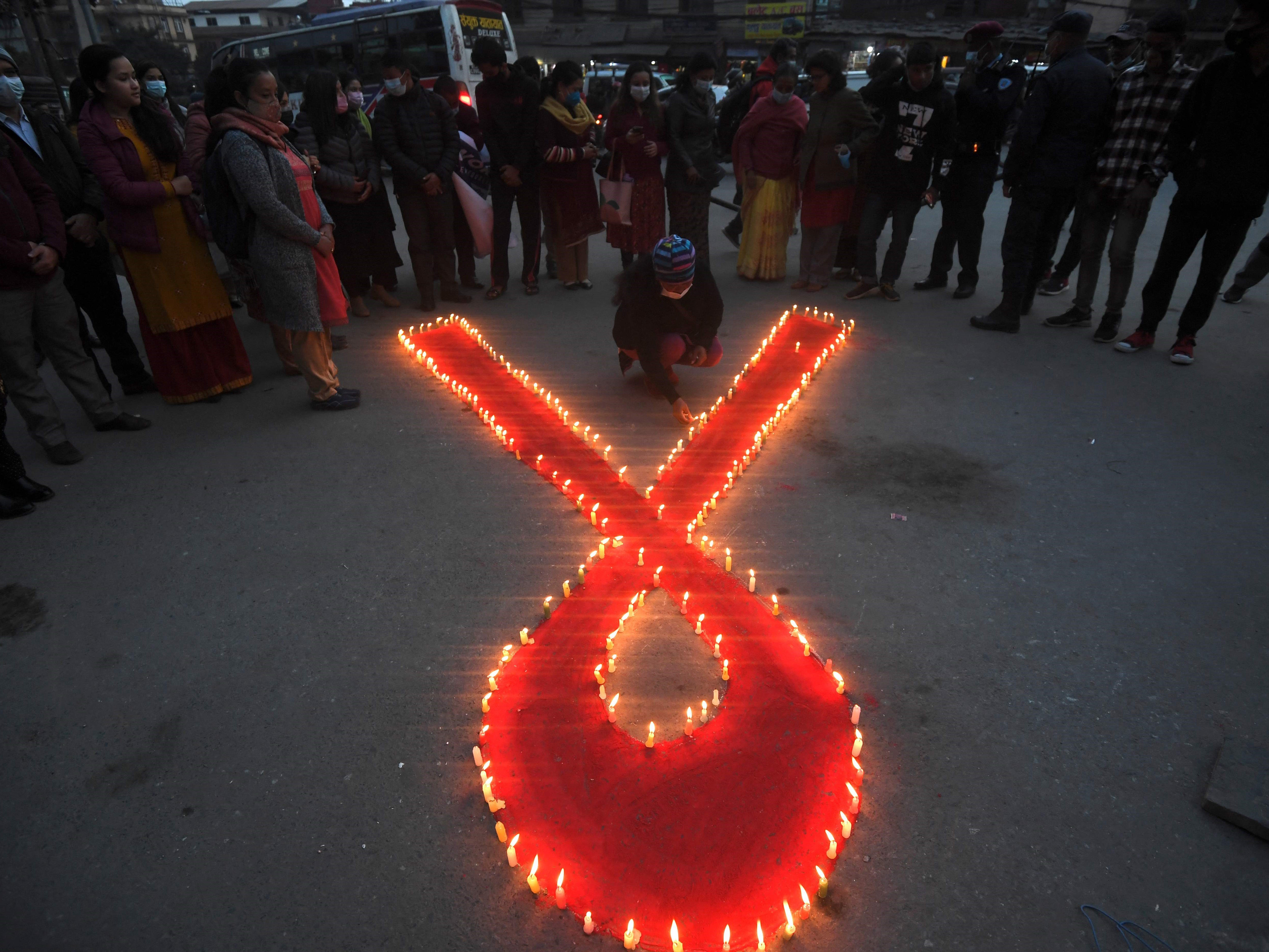 Seorang relawan menyalakan lilin berbentuk pita merah dalam acara penyadaran pada malam Hari AIDS Sedunia di Kathmandu, Nepal. 