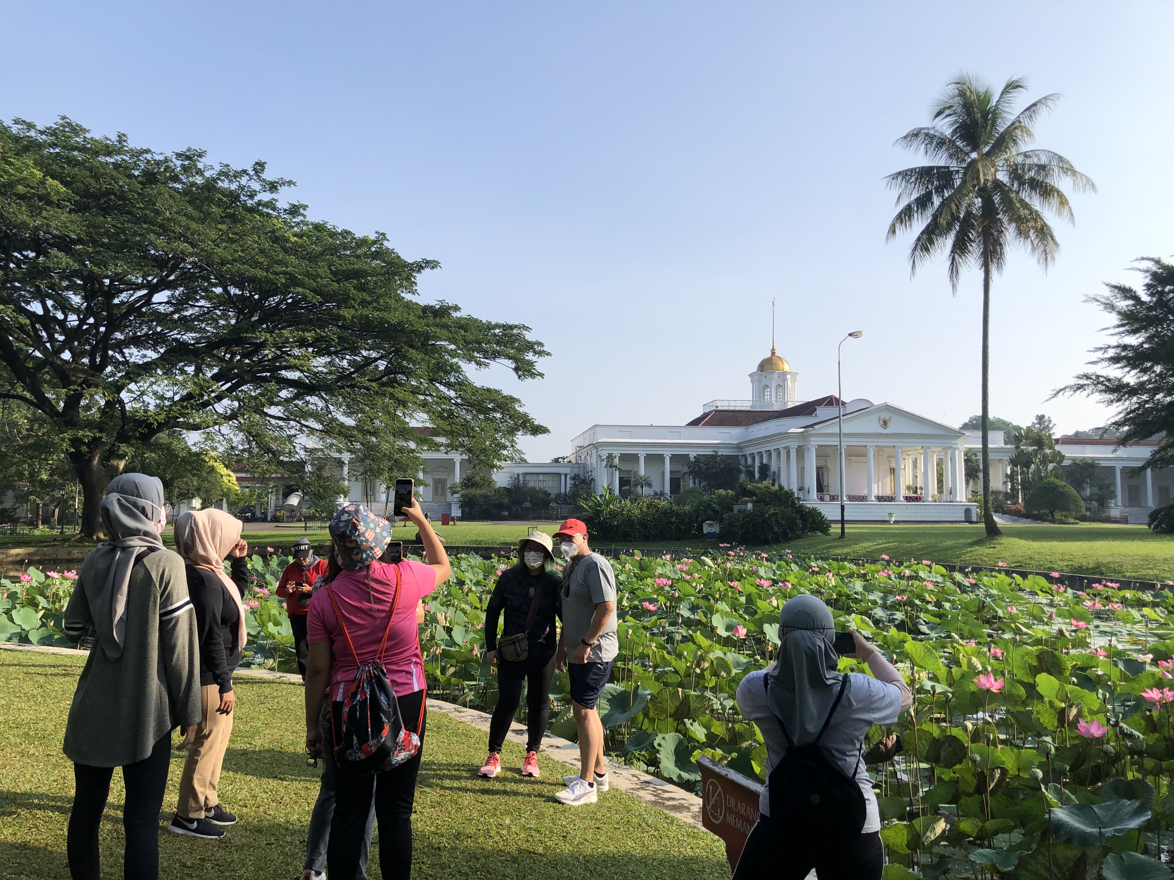 Warga berfoto dengan latar Istana Bogor saat berwisata ke Kebun Raya Bogor, Jawa Barat, Minggu (26/09/2021).