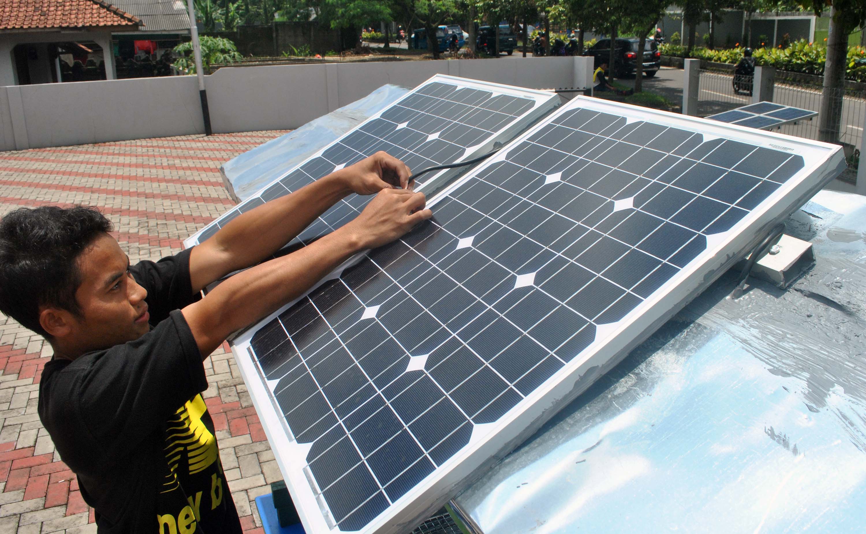 Pekerja memasang instalasi panel surya di gerobak angkringan di Bogor.