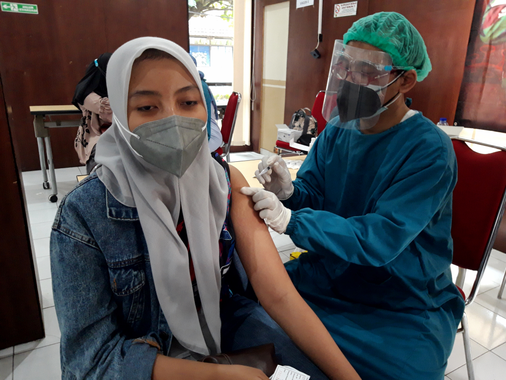 Seorang warga tengah divaksinasi oleh petugas dari Poltekkes Malang