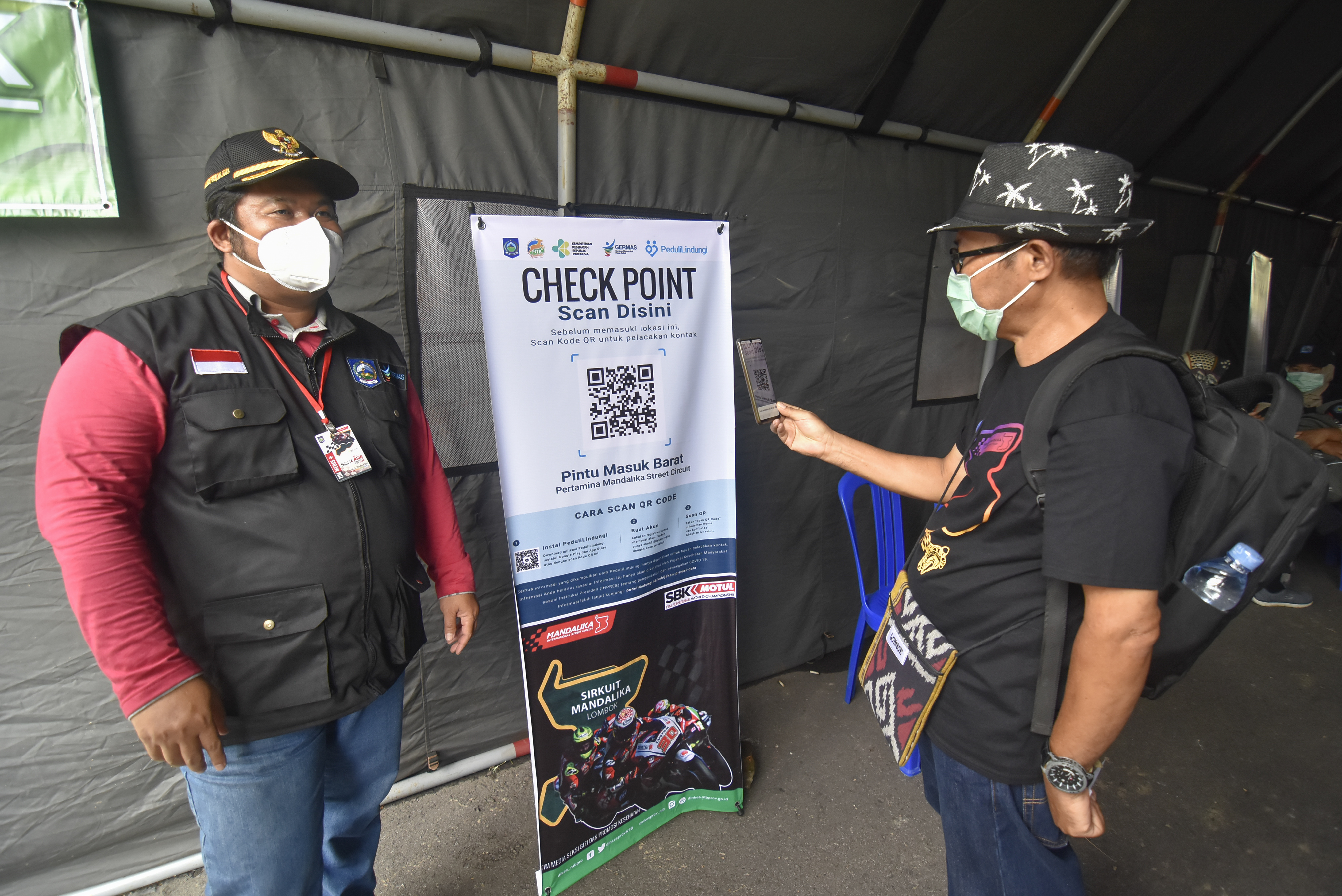 Warga memindai plikasi PeduliLindungi saat hendak menonton balap motor Idemitsu Asia Talent Cup di Sirkuit Mandalika, NTB. 