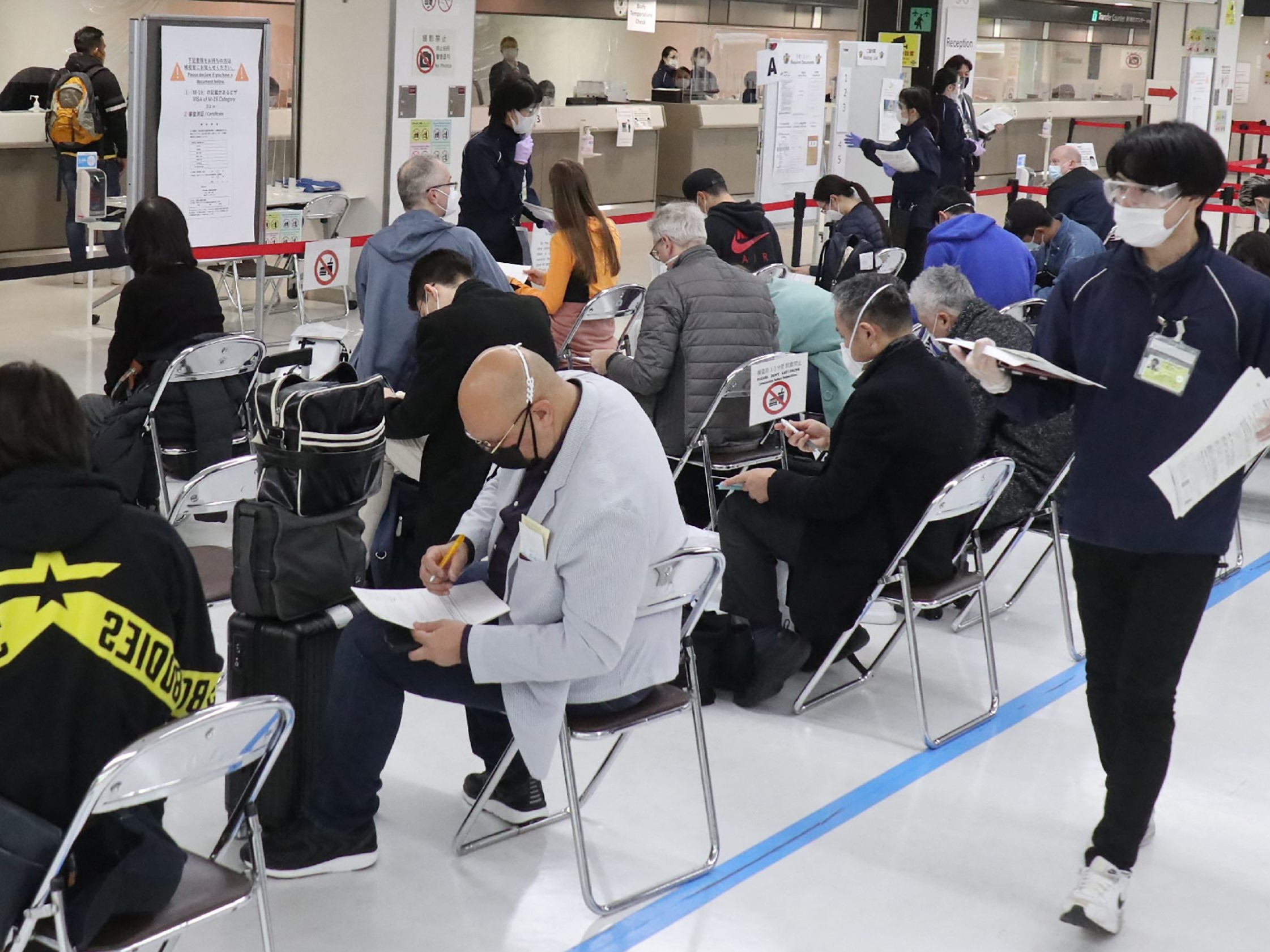 Pelancong, sebagian besar orang Jepang dan beberapa penduduk asing, menunggu di tempat karantina setelah kedatangan di Bandara Narita.