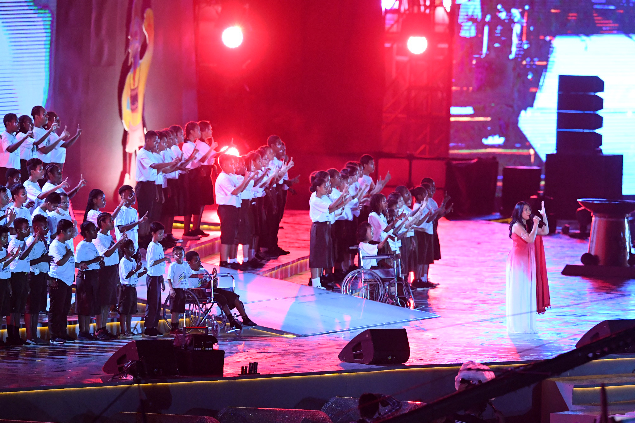 Penyanyi Anggun C. Sasmi (kanan) menyanyikan lagu Indonesia Raya bersama anak-anak disabilitas saat Upacara Pembukaan Peparnas Papua