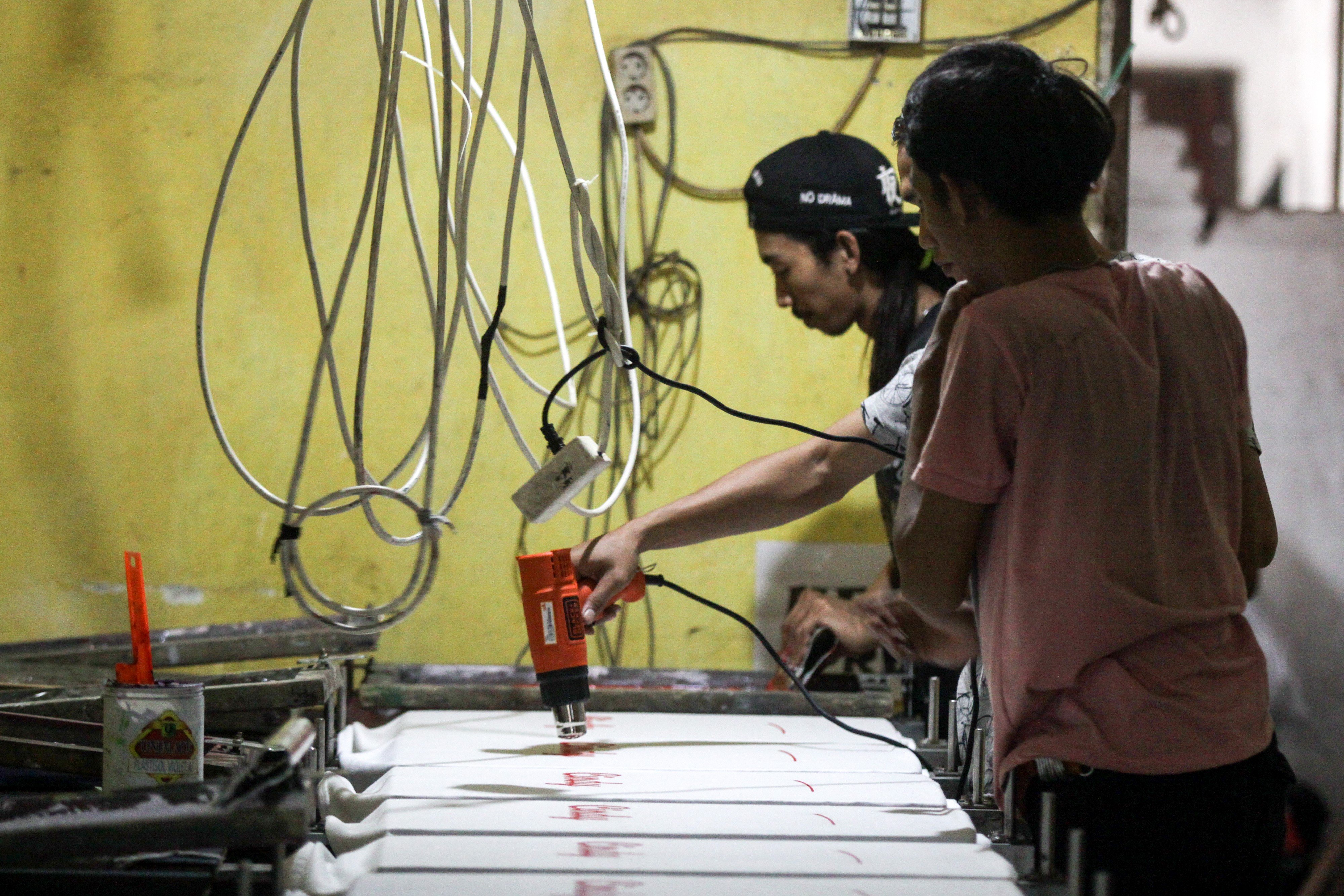 Pekerja melakukan proses pengeringan kaos yang baru disablon di industri kreatif kawasan Bangsri, Sukodono, Sidoarjo, Jatim, Kamis (4/11).