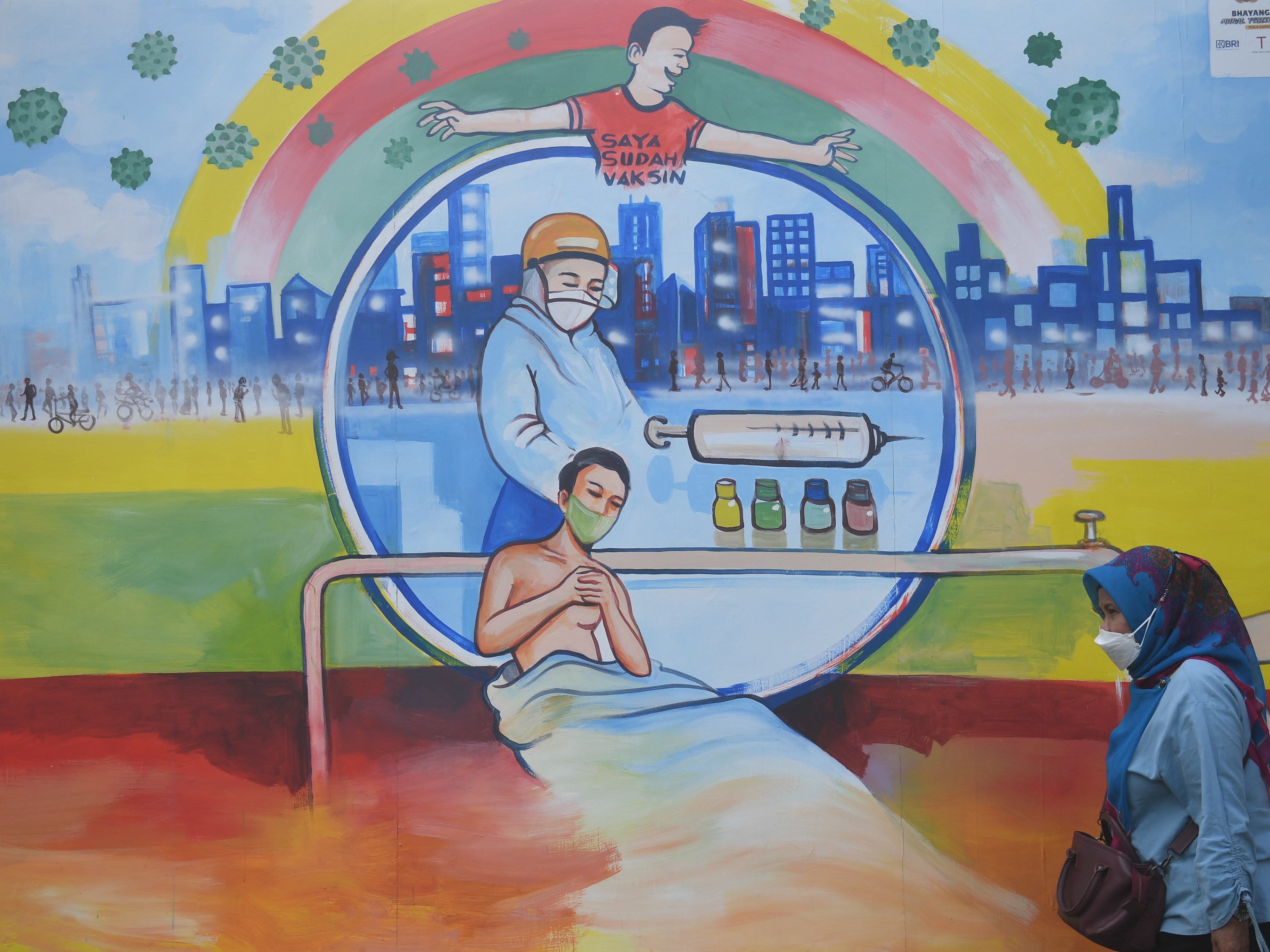 Warga melintas di dekat mural bertema covid-19 di Jakarta, Rabu (1/12/2021).