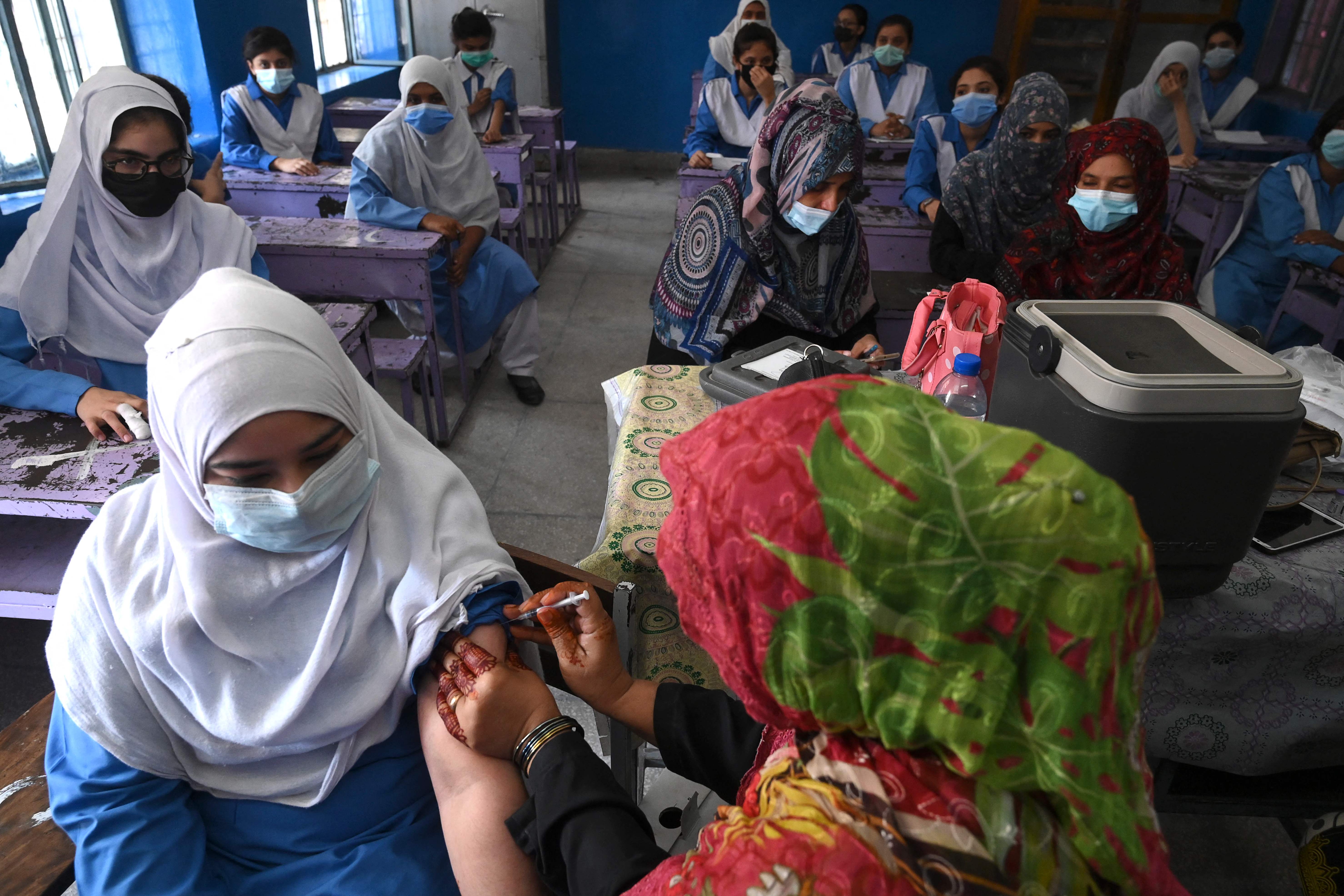 Petugas medis menyuntikkan vaksin Covid-19 Pfizer kepada para pelajar di sebuah sekolah di Lahore, Pakistan.  