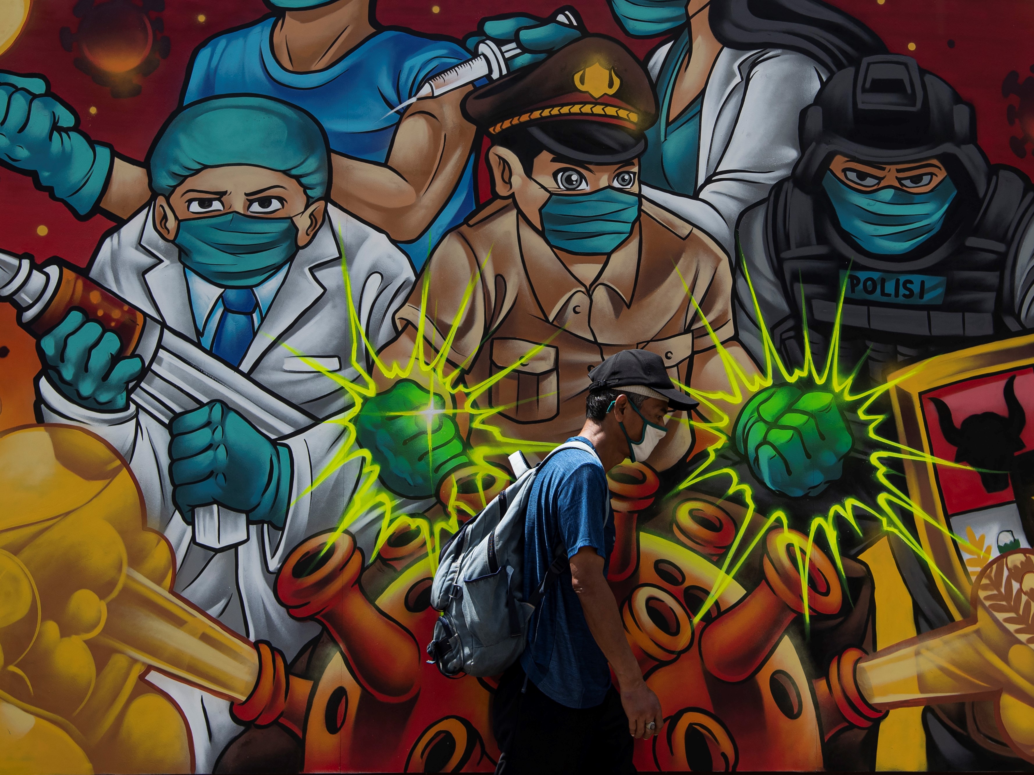 Warga melintas di depan tentang mural covid-19 di Jakarta, Selasa (2/11/2021).