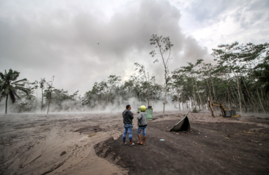 Warga melihat material awan panas erupsi Gunung Semeru yang mengalir di Sumber Wuluh, Lumajang, Jawa Timur, Minggu (5/12/2021).