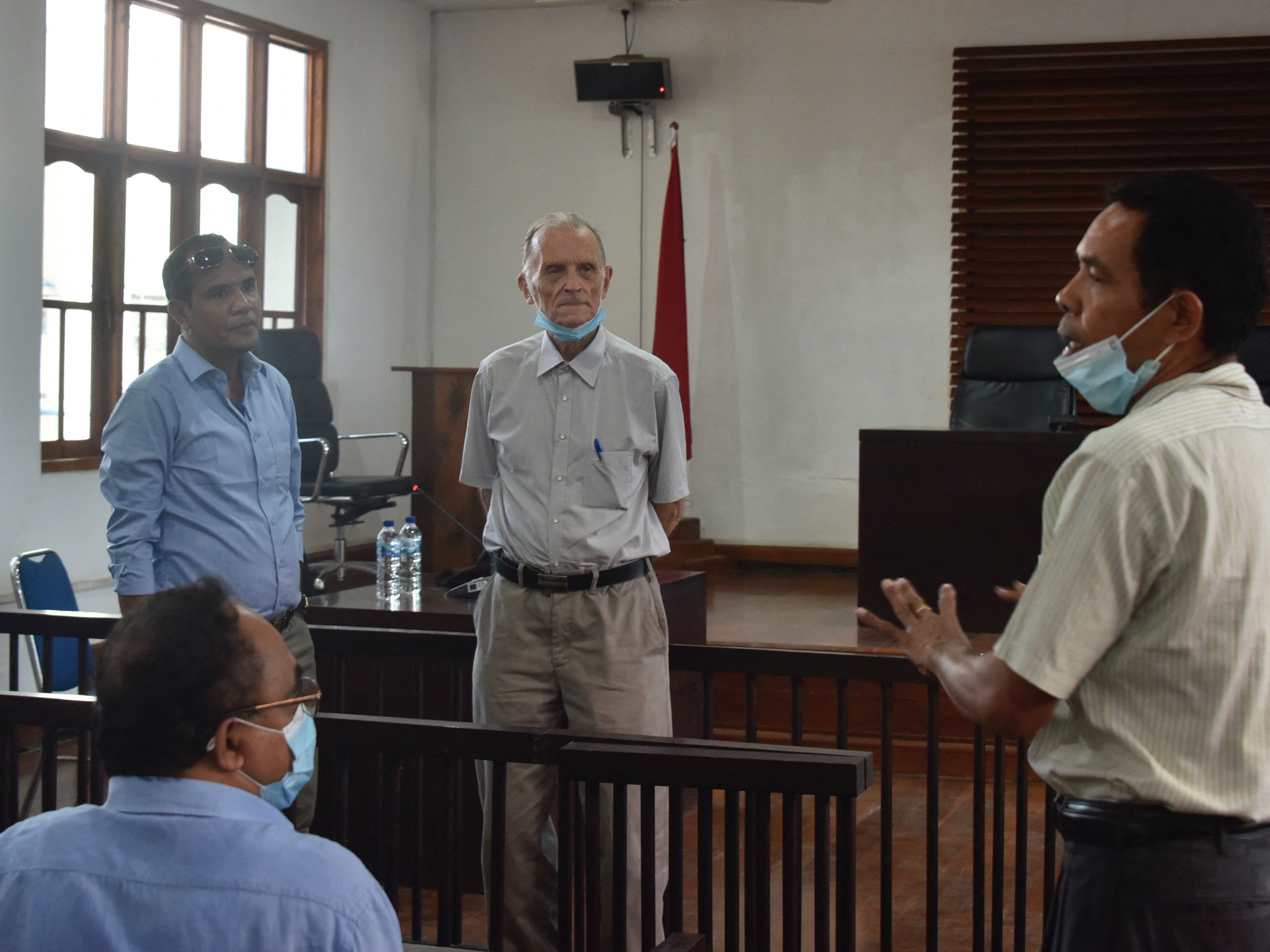 Gambar ini diambil pada 9 Juni 2021 menunjukkan pendeta AS yang dipecat Richard Daschbach (tengah) bersiap menghadapi perssidangan.idan