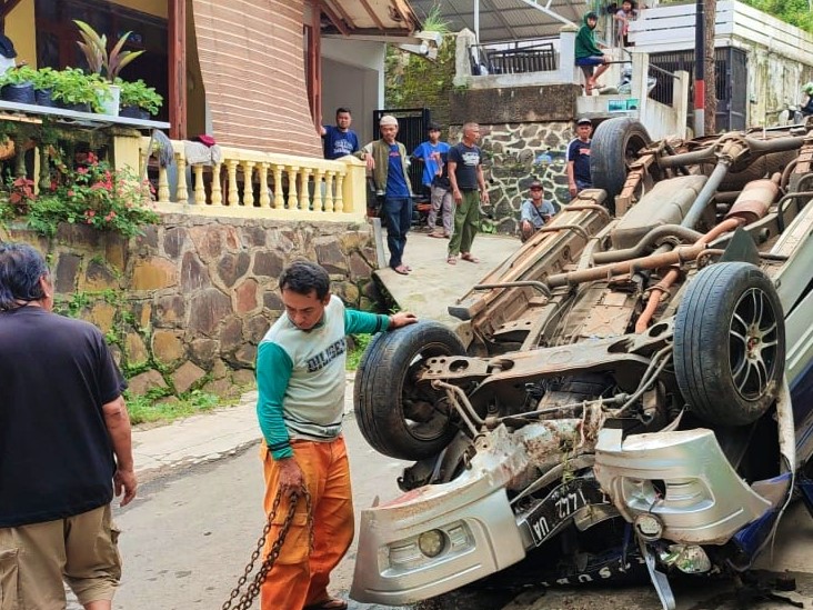 Warga membantu evakuasi mobil yang terguling di Kampung Pagersari, Desa Pagerwangi, Kecamatan Lembang, Bandung Barat, Minggu (12/12).