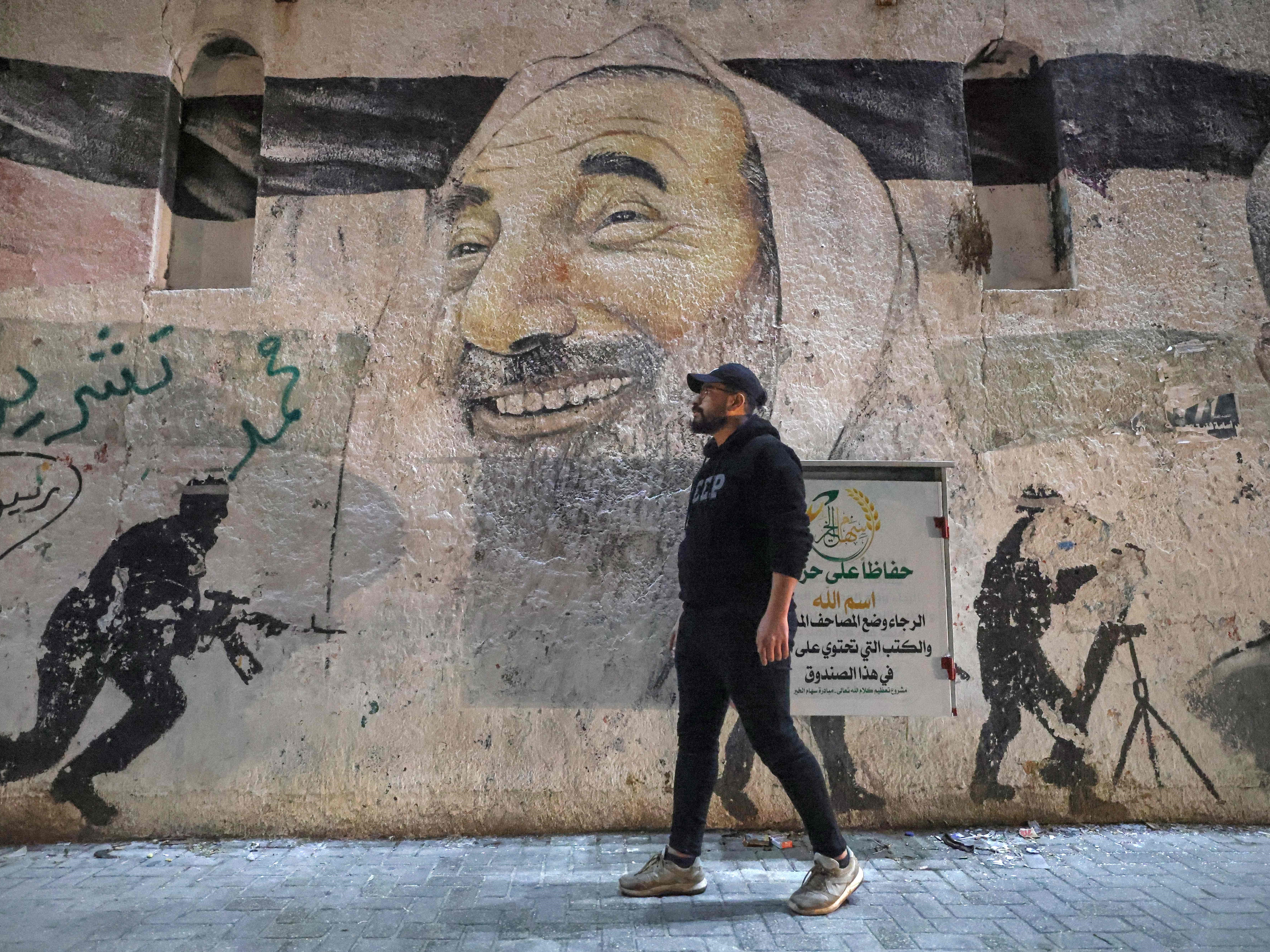 Seorang pria berjalan melewati lukisan dinding yang menggambarkan mendiang pemimpin spiritual gerakan Hamas Sheikh Ahmed Yassin.