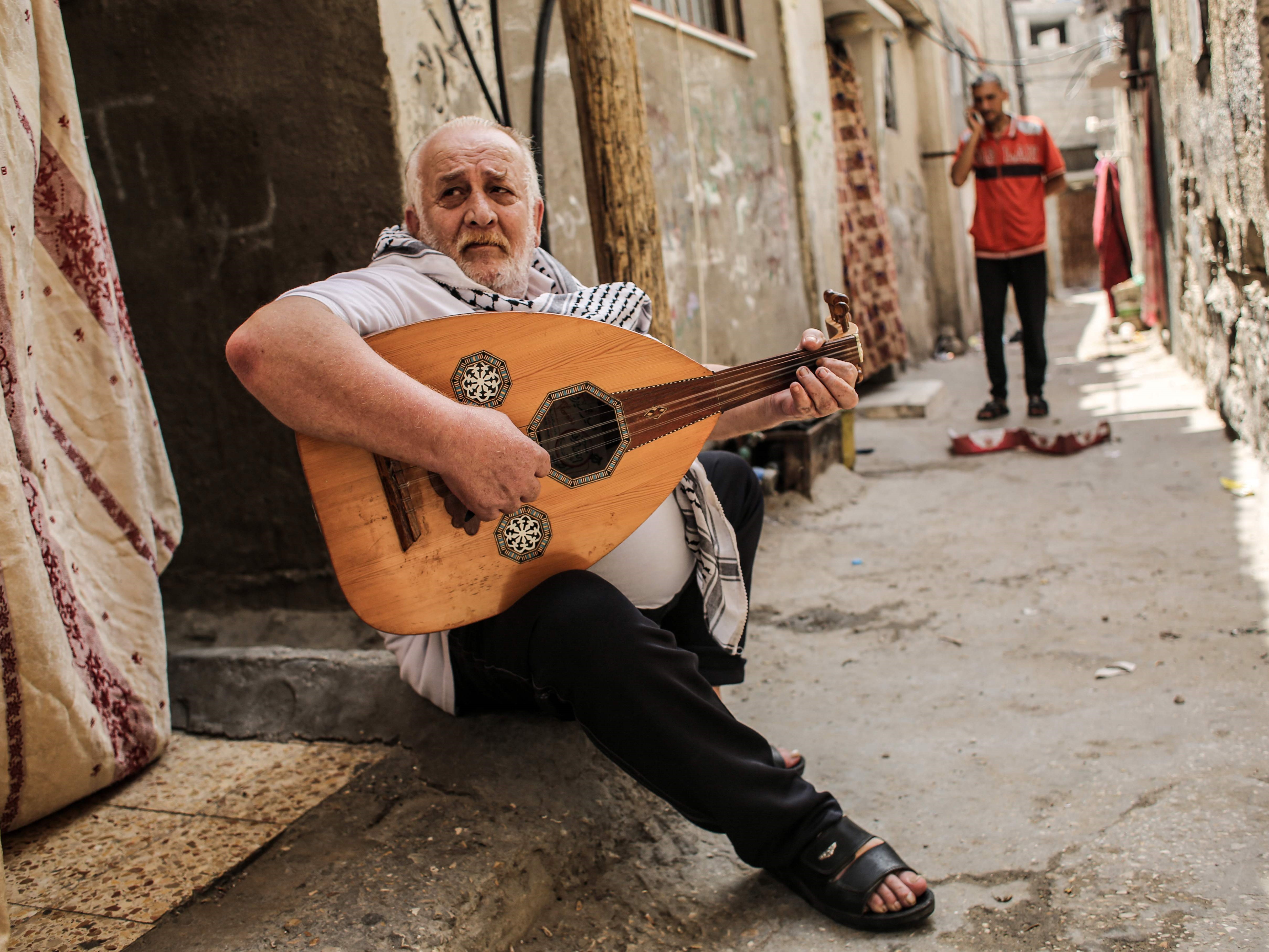 Tawfiq Shanaa, 66, memainkan oud saat membawakan lagu-lagu tradisional Palestina di luar rumahnya di kamp Rafah untuk pengungsi Palestina.