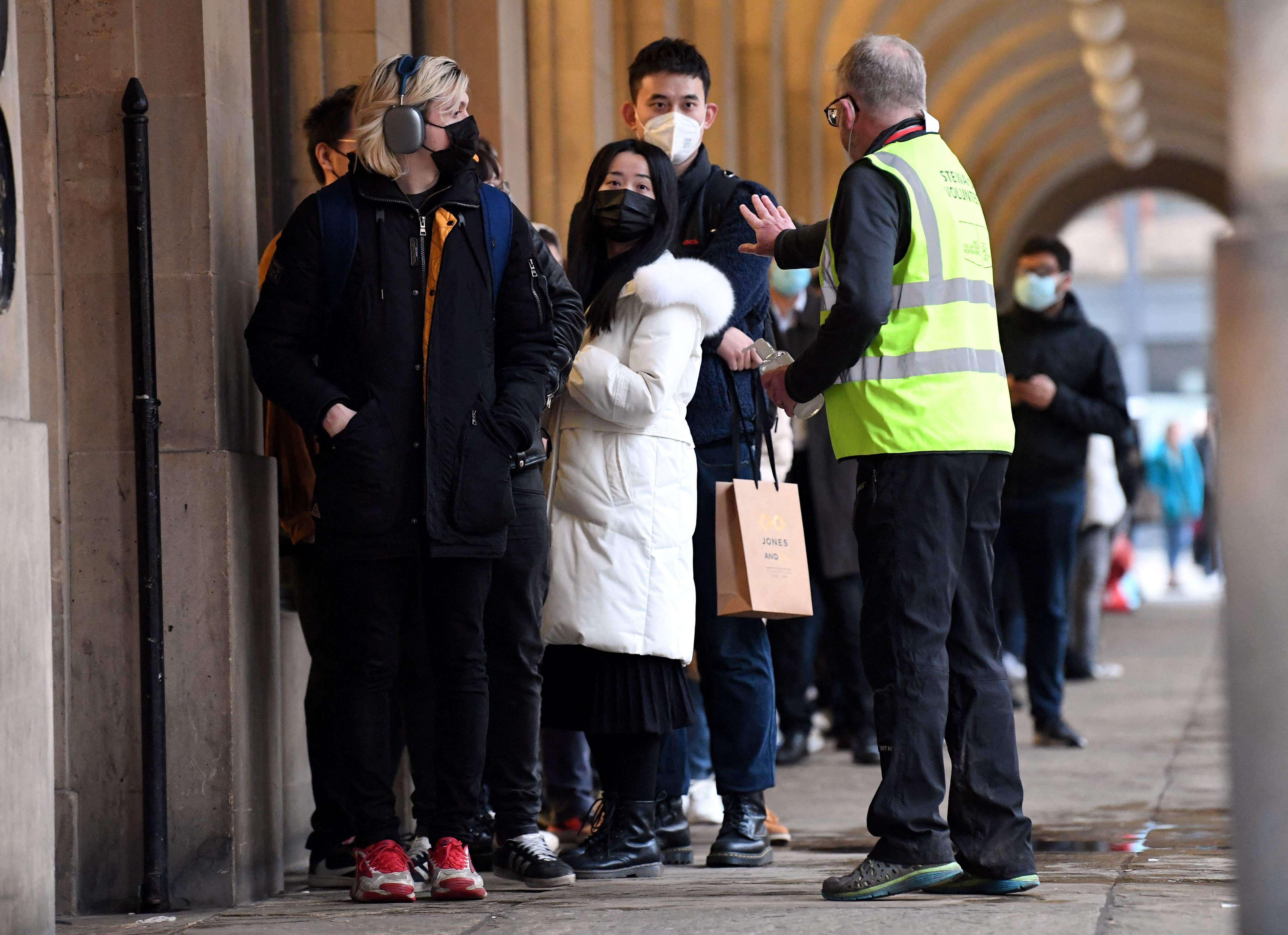 Seorang petugas mengatur barisan warga yang hendak melakukan vaksinasi Covid-19 di Manchester, Inggris, Selasa (14/12).